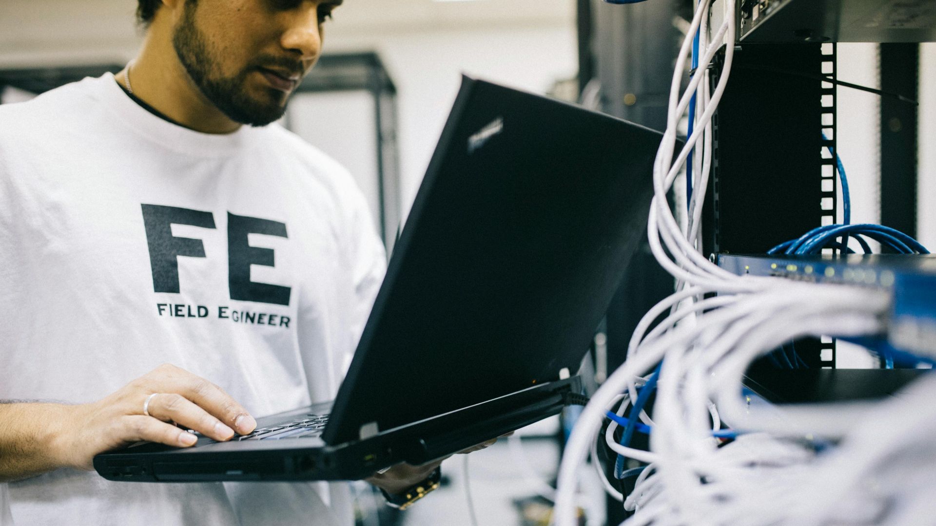 Crop focused Asian engineer in white shirt using modern netbook while working with hardware