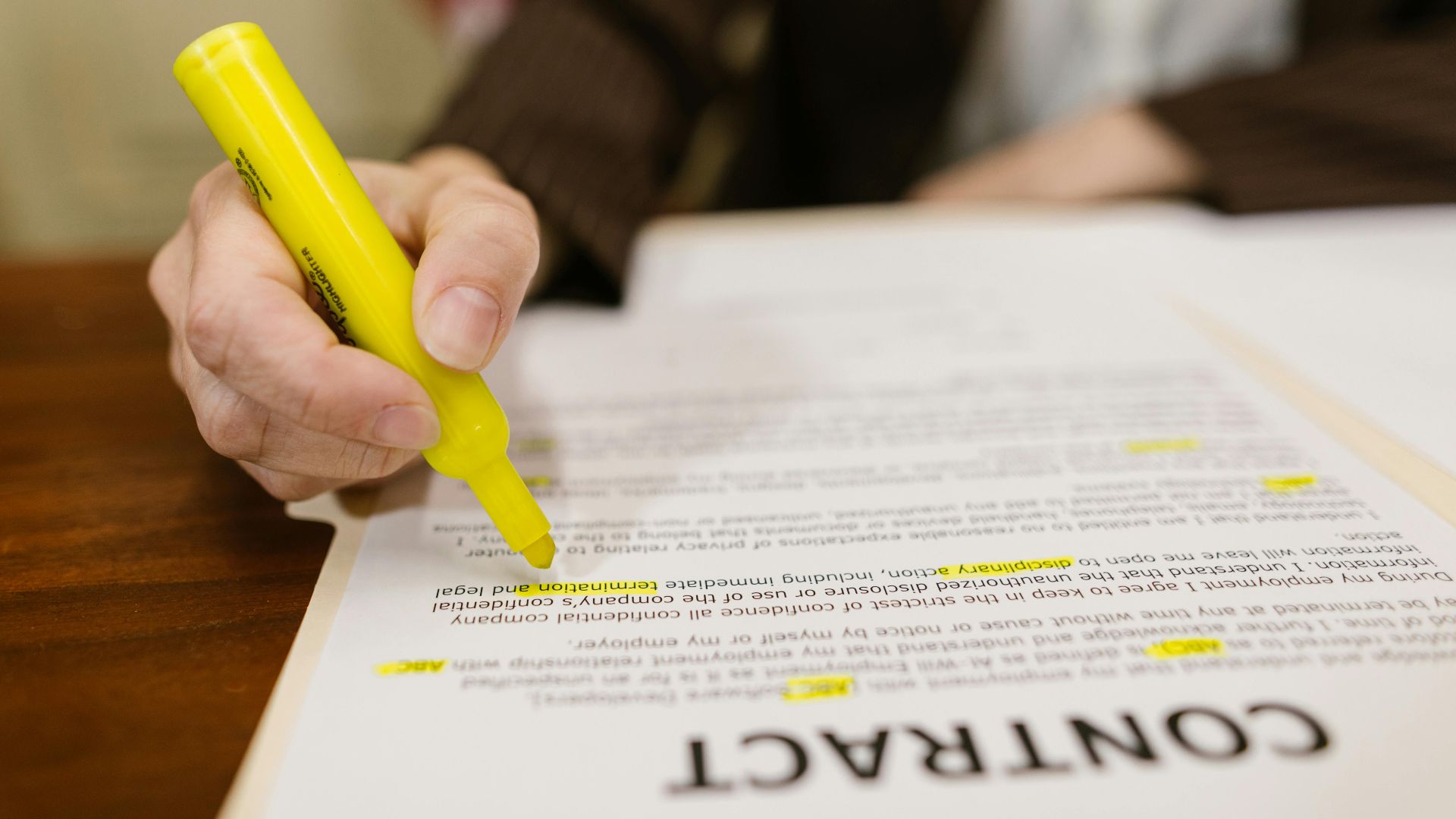 A close-up of a hand highlighting a contract, emphasizing important legal terms.