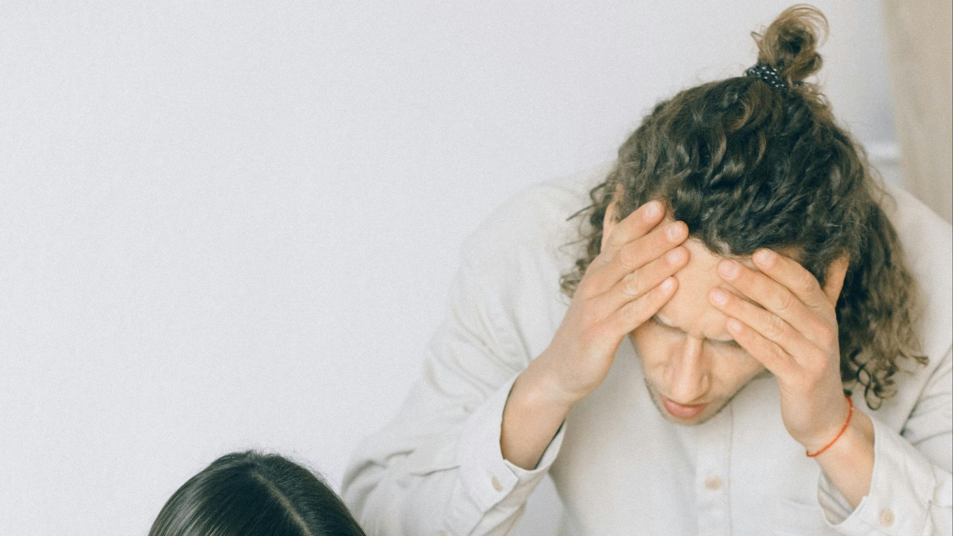 Young couple in discussion over financial papers, looking stressed at a table indoors.
