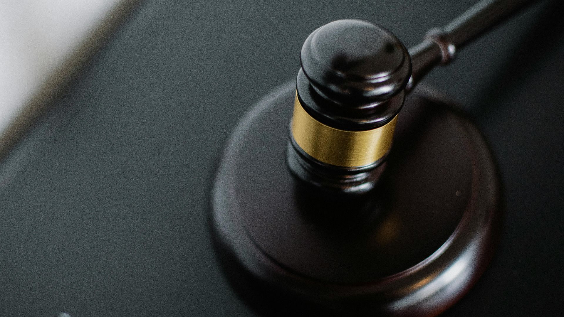Close-up of a wooden judge's gavel on a black desk, symbolizing justice and law.