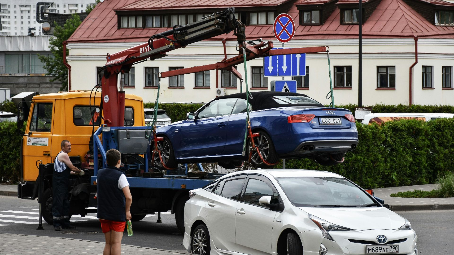 Towing a blue Audi convertible in a bustling city street.
