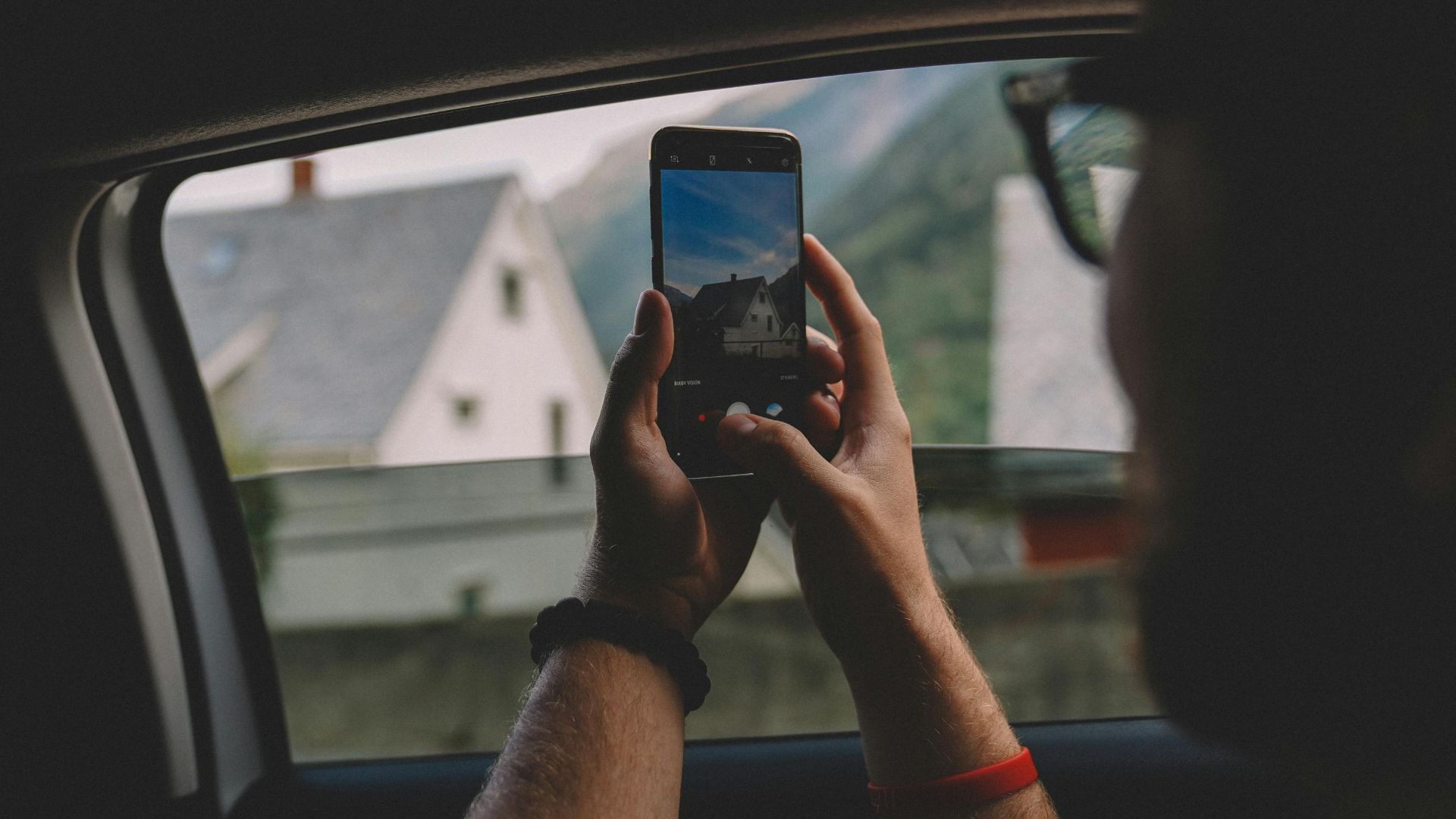 Person takes photo of scenic view from car window with smartphone in Norway.