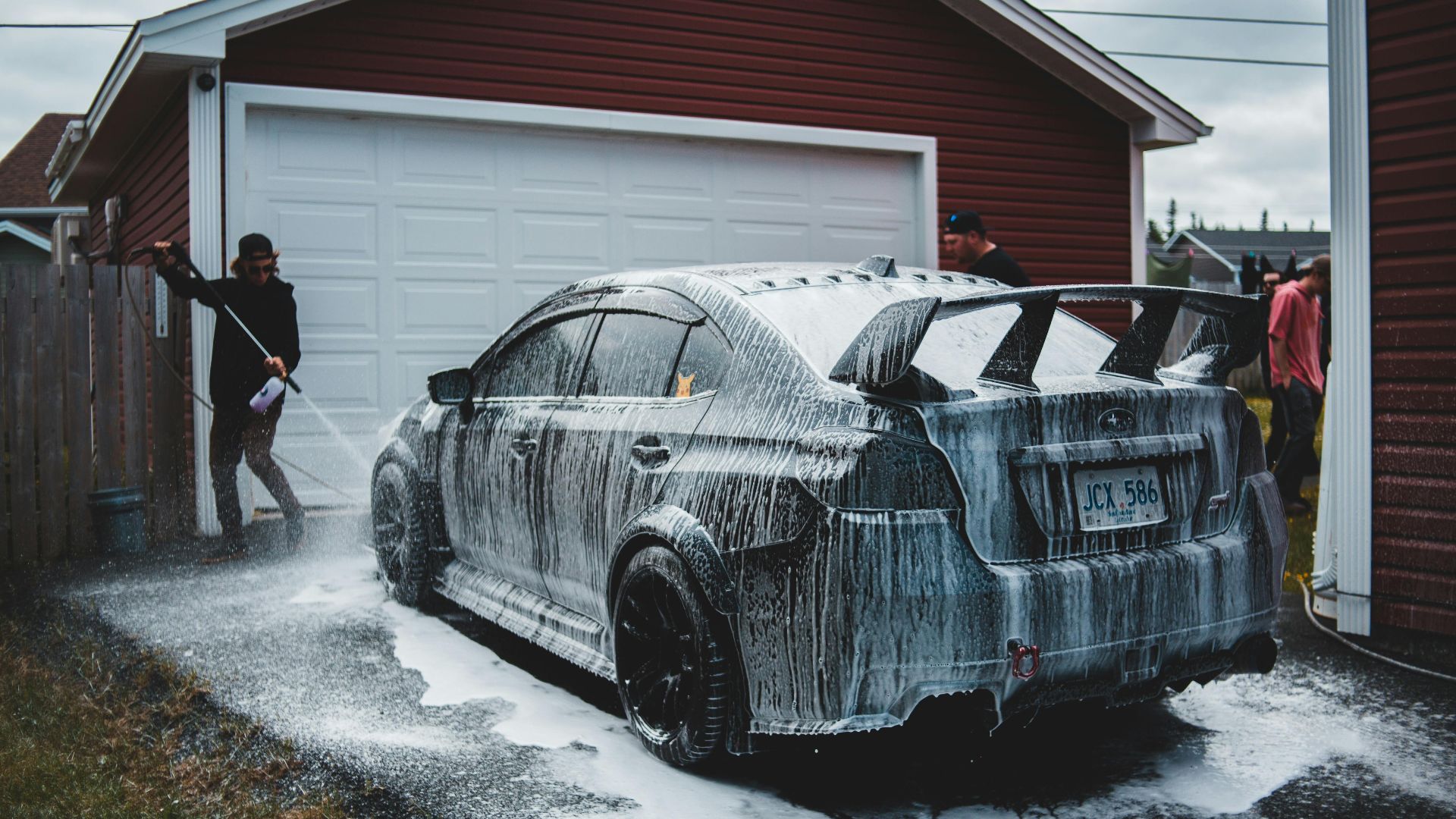 Outdoors car washing scene with a sports car and casual washers.