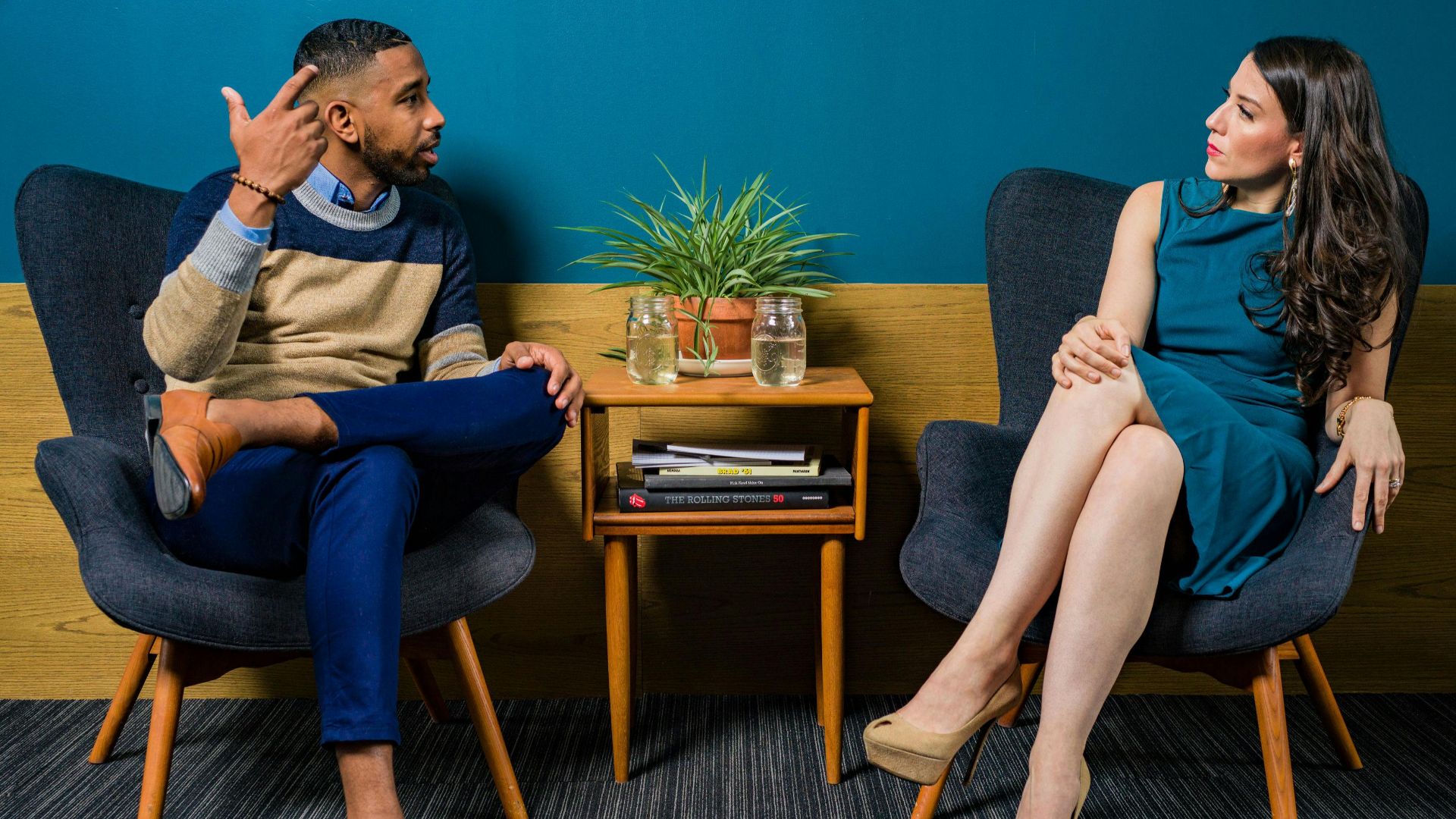 Two professionals in business attire engage in a thoughtful discussion sitting in a stylish, modern room.