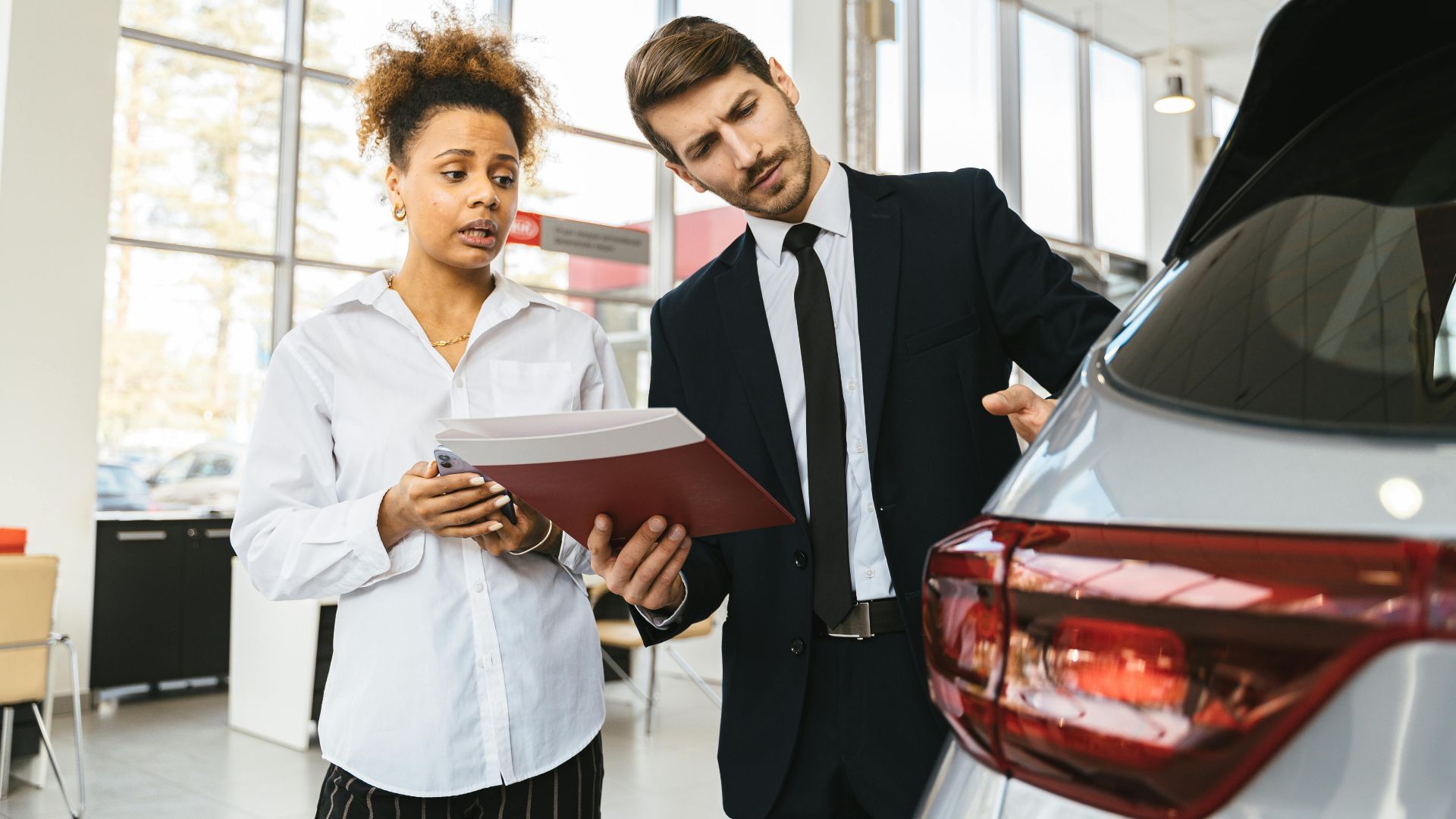 A professional consultation at a car dealership involving a sales agent and a customer discussing a vehicle purchase.