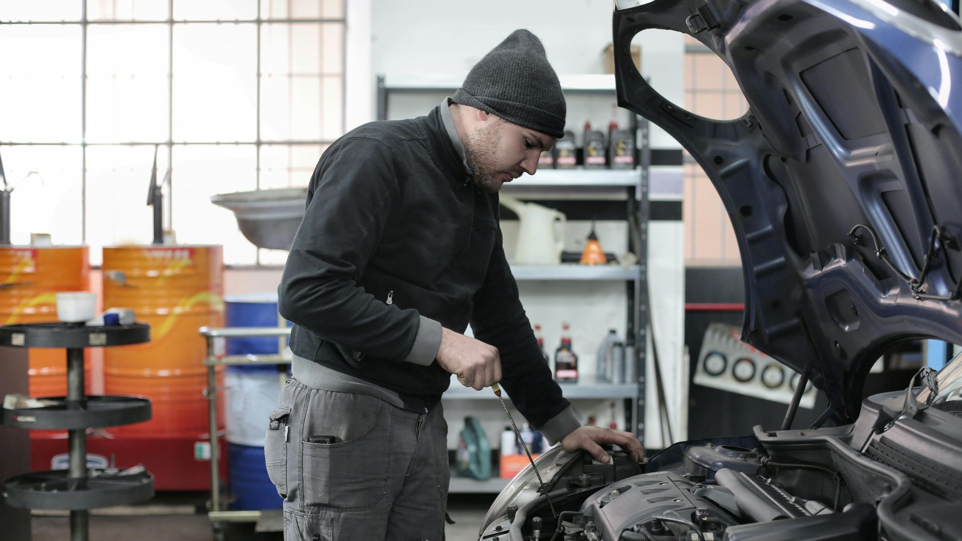 Mechanic checking a car engine in a garage, ensuring quality maintenance and repair.
