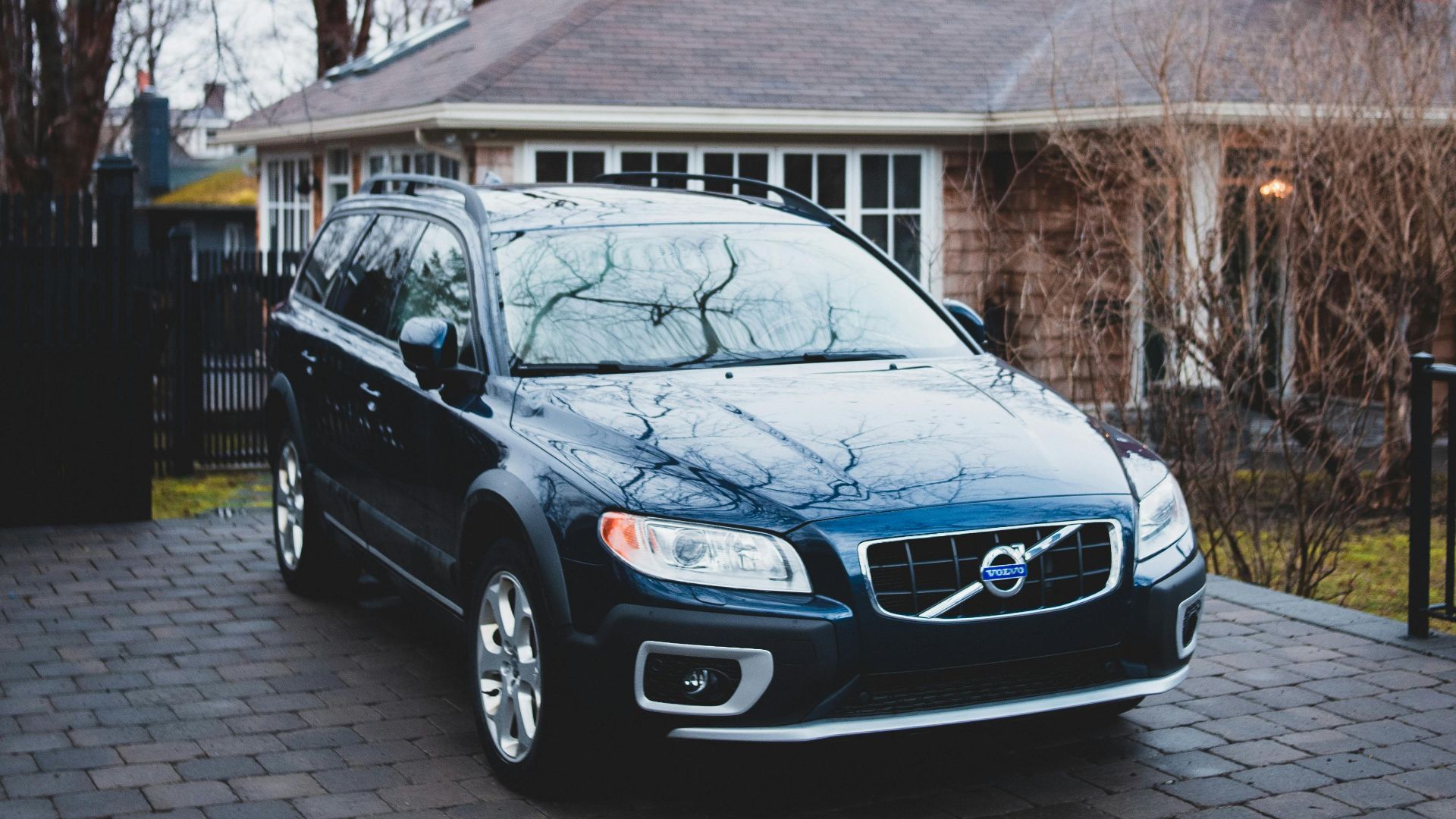 A stylish SUV parked in front of a suburban house during autumn.