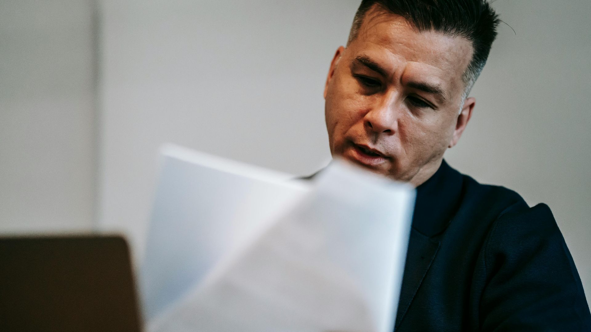 Professional man intently reviewing paperwork at his workstation indoors.