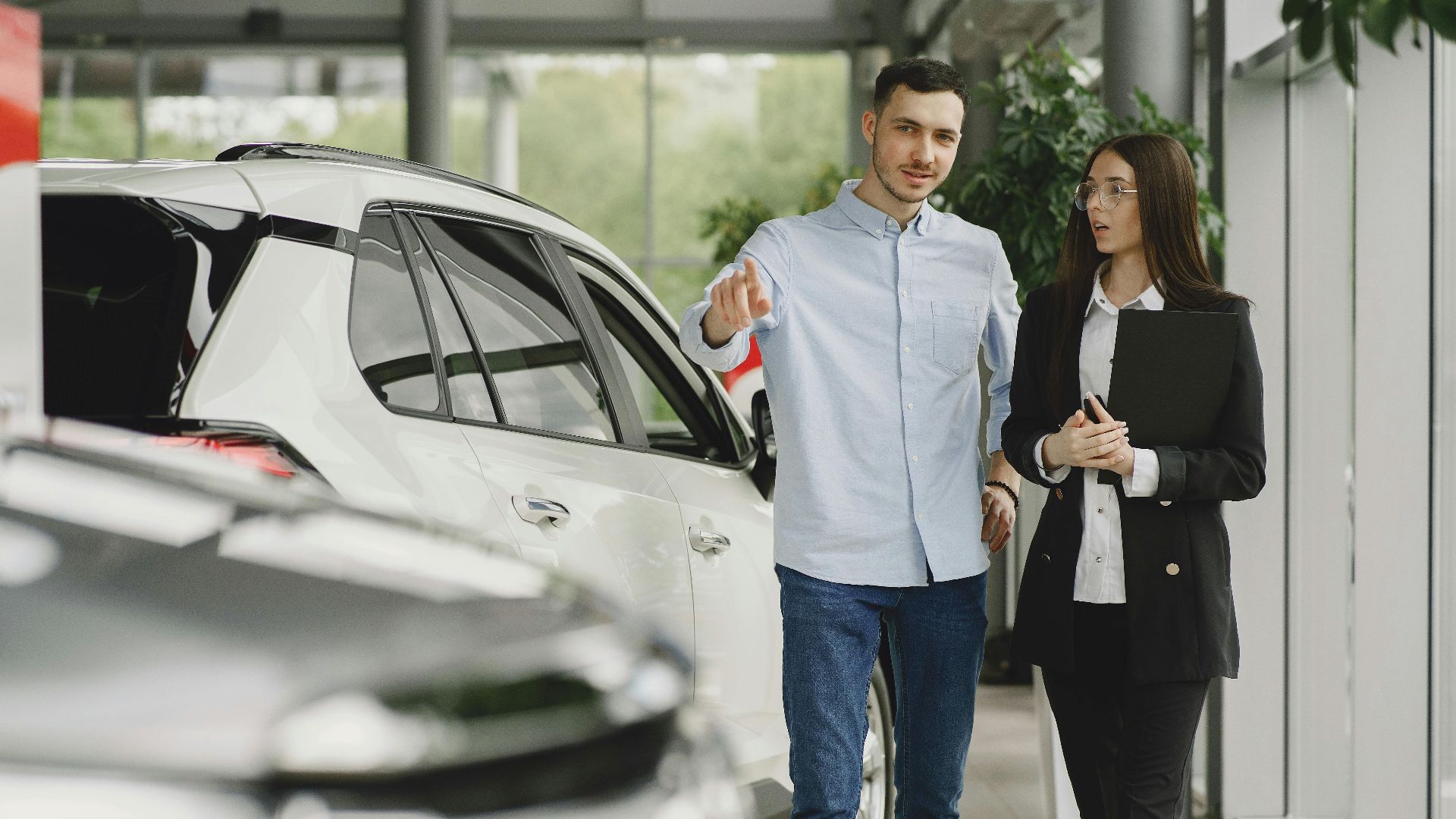 Customer and salesperson discussing a vehicle inside a modern car dealership showroom.