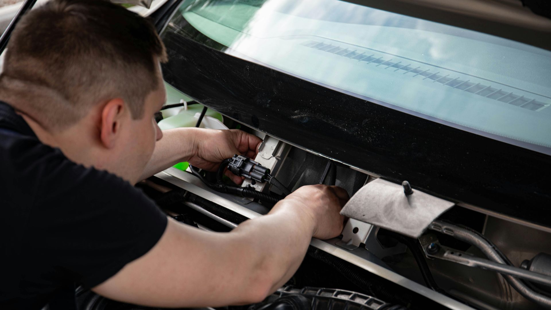 A mechanic working on car engine repairs inside a workshop setting.