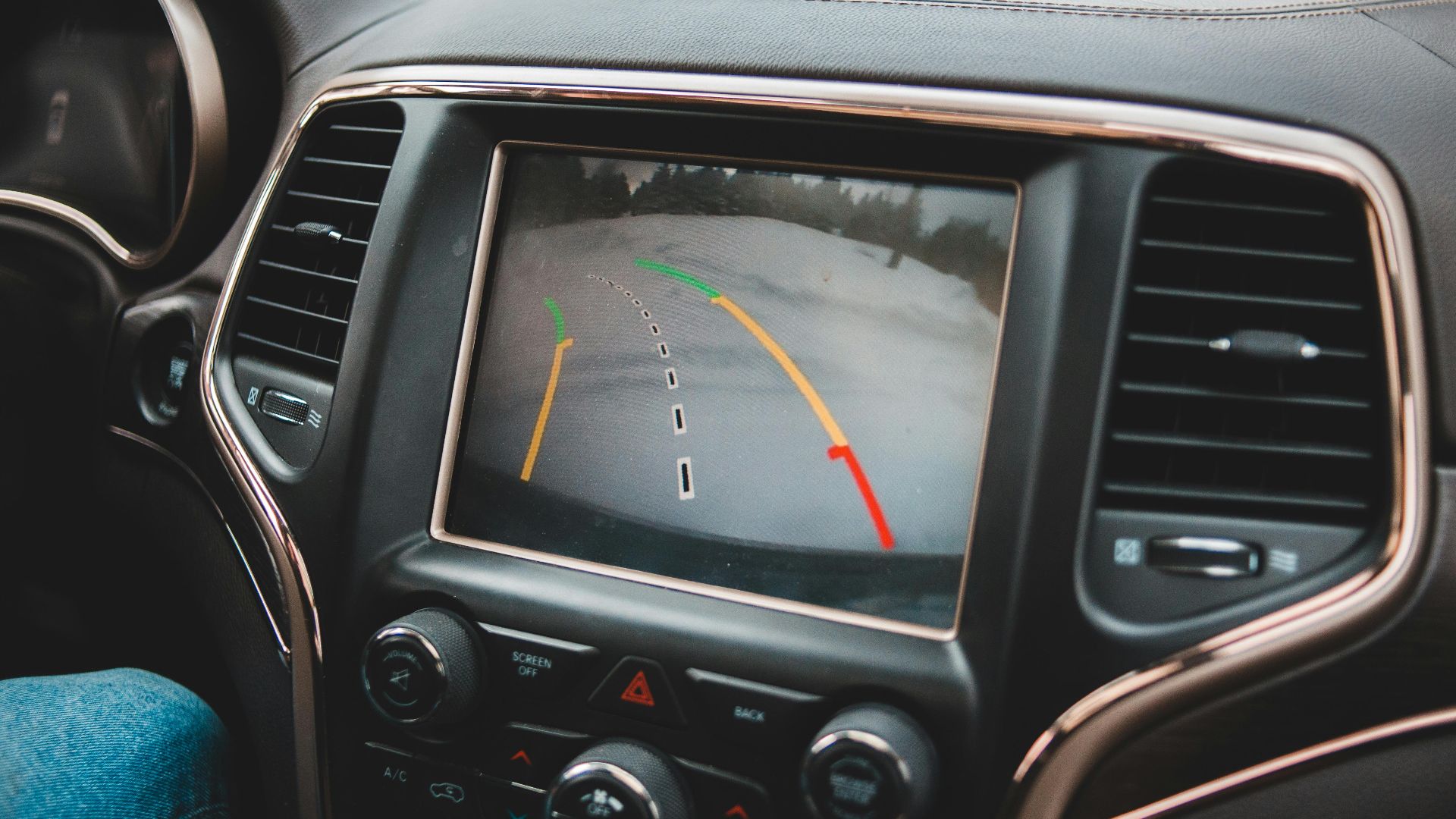 Close-up of a car's dashboard showing a rearview camera display for parking assistance.