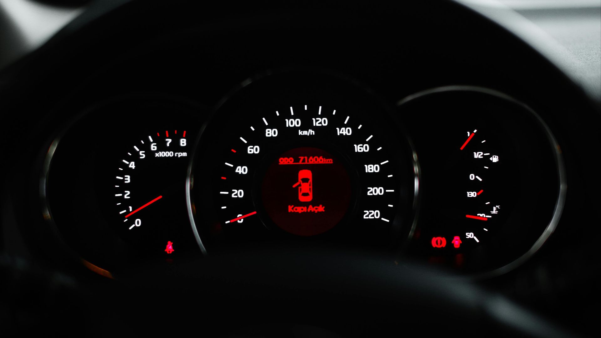 Car dashboard showing a warning light with various dials and gauges in focus.