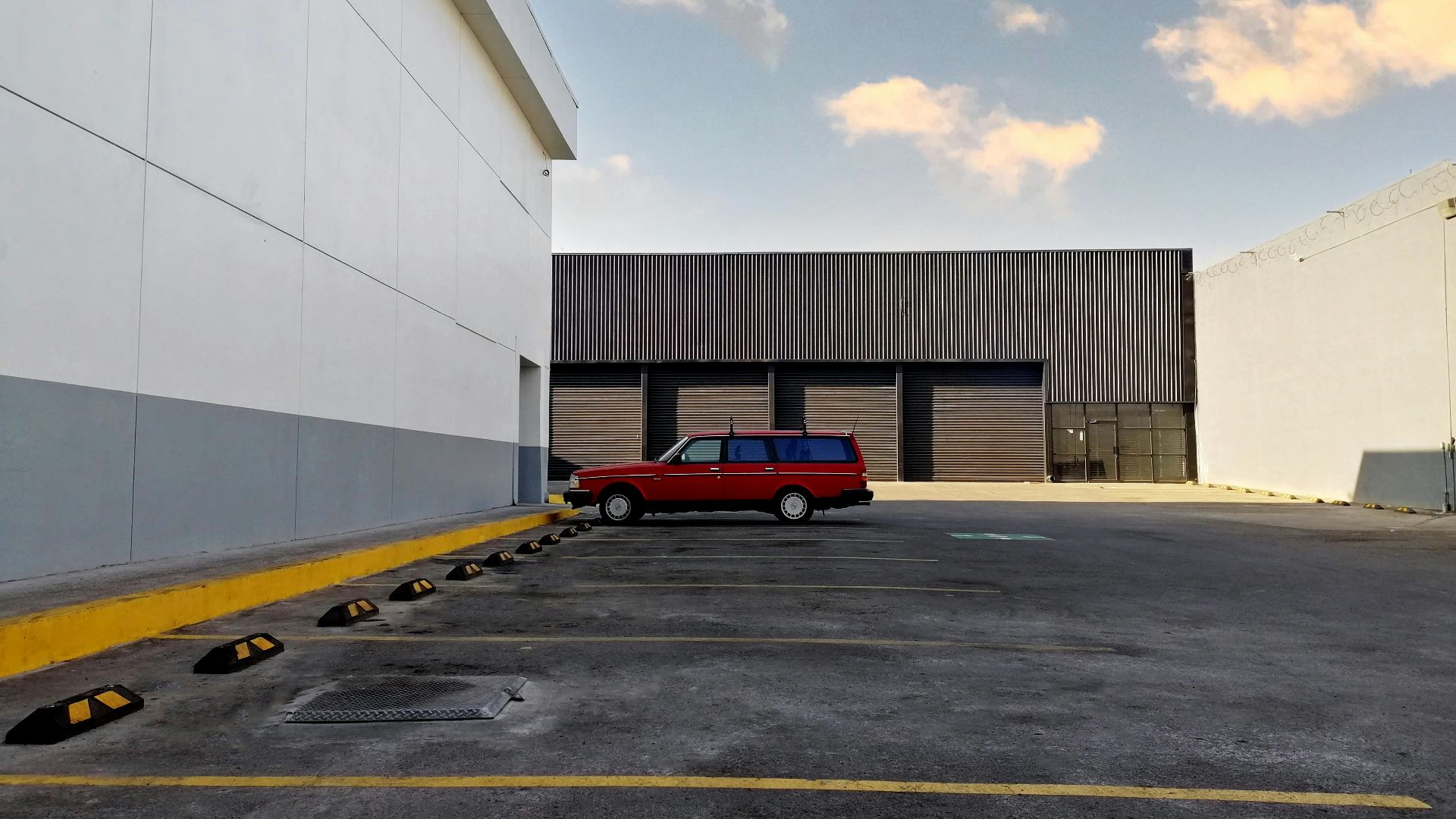 A red vintage station wagon parked in an empty urban parking lot under a clear sky in Tijuana, Mexico.