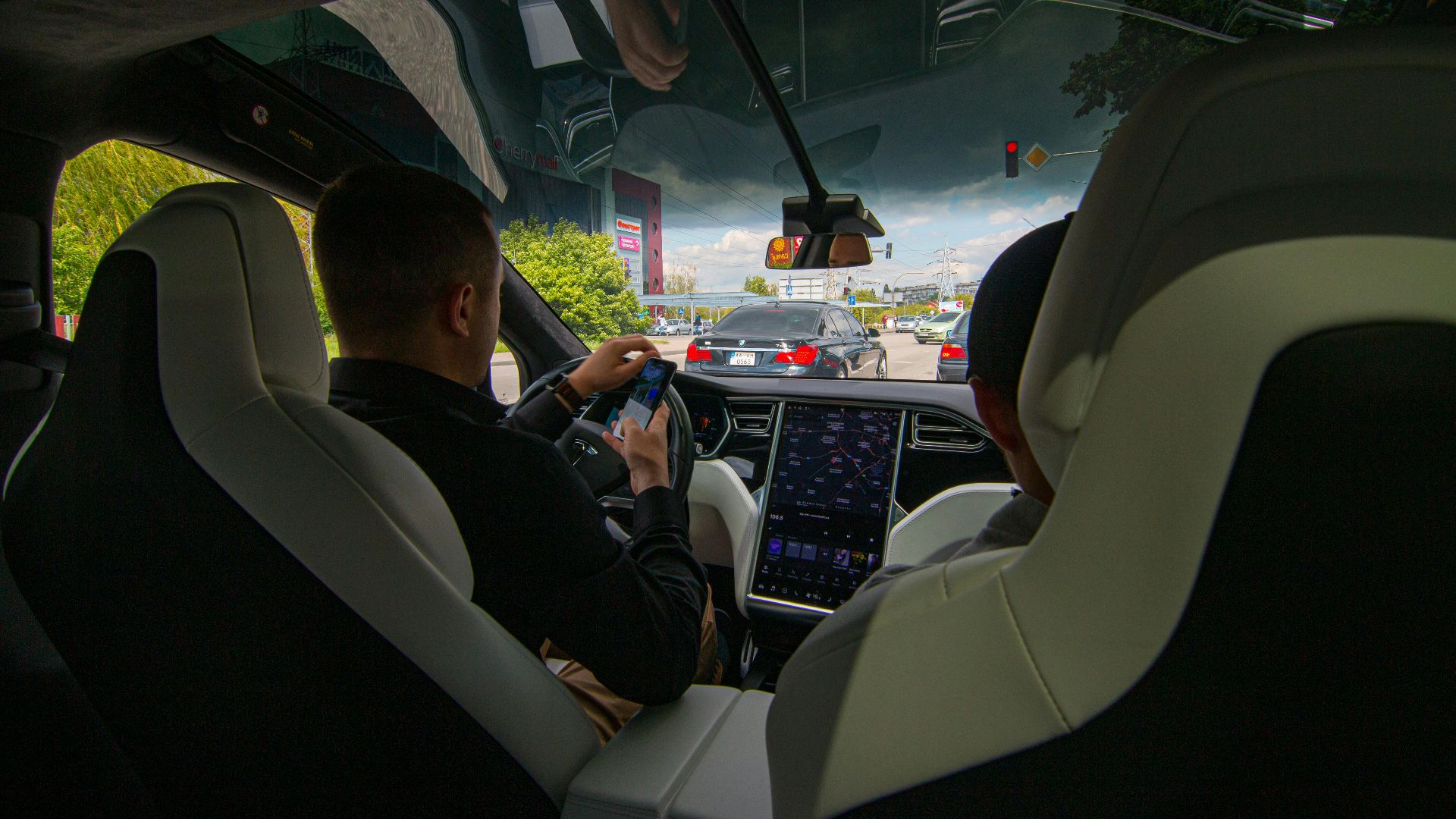 Inside a Tesla vehicle in city traffic, showcasing modern technology and urban driving.
