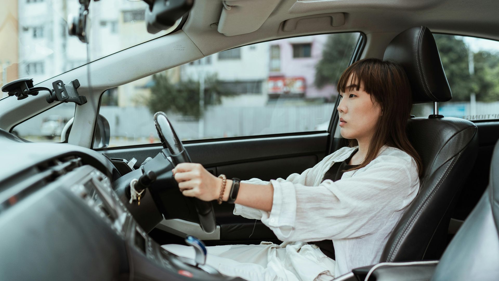 Confident young woman driving in the city, focused and pensive.
