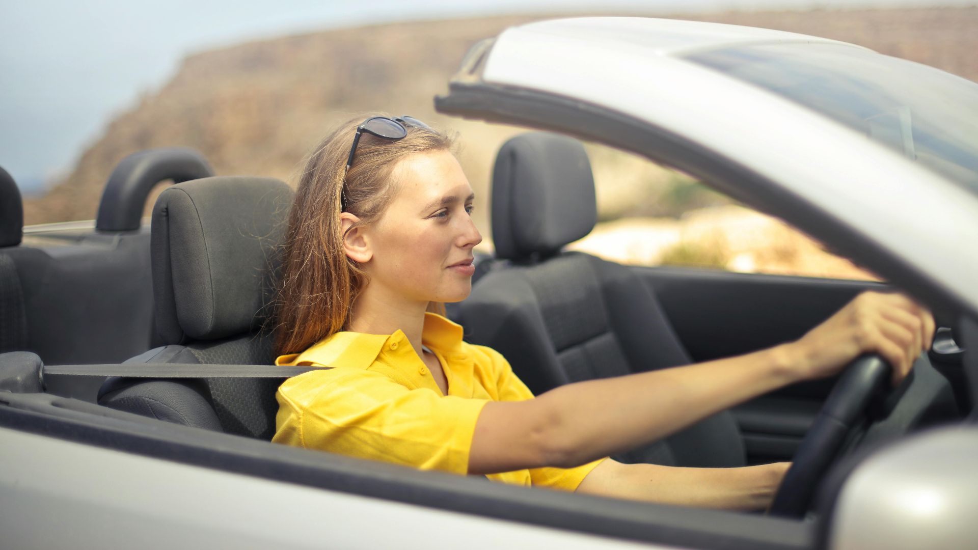 A young woman enjoys driving a convertible on a sunny day in Malta.