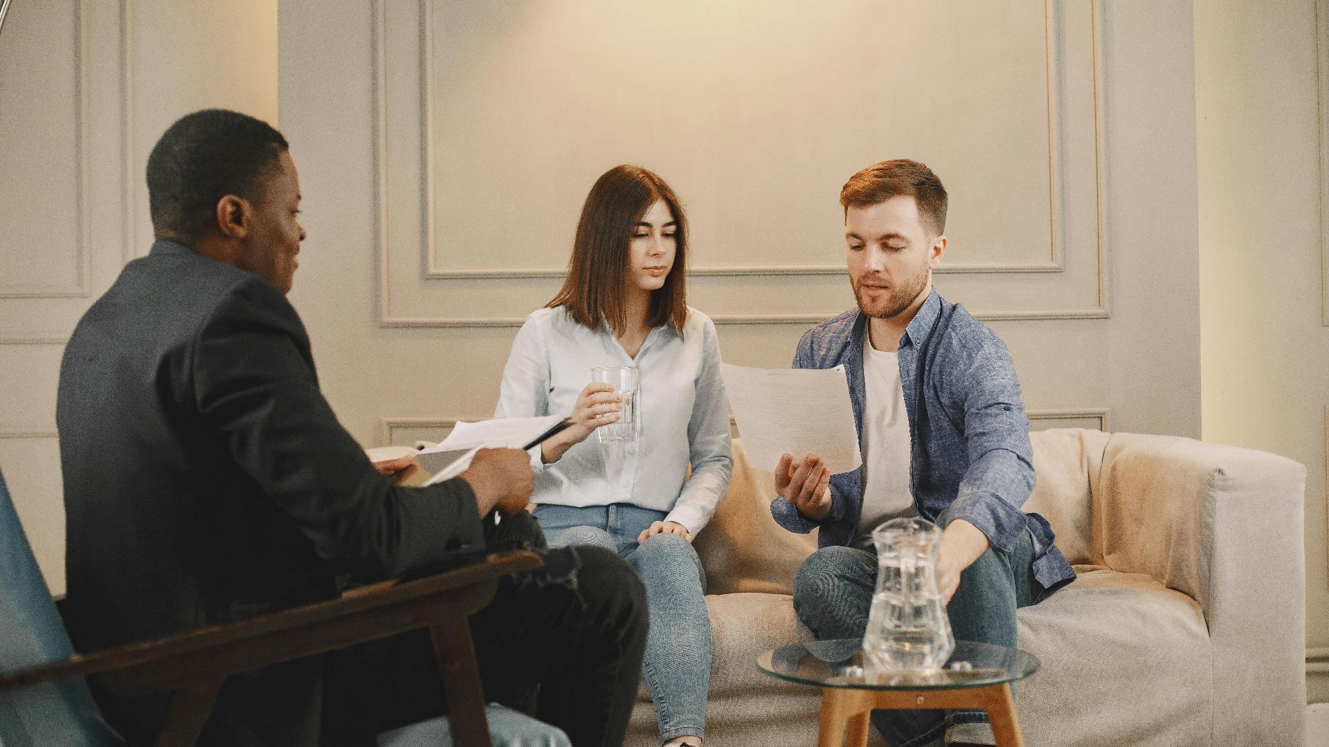 Therapist counseling couple with documents in contemporary office setting.