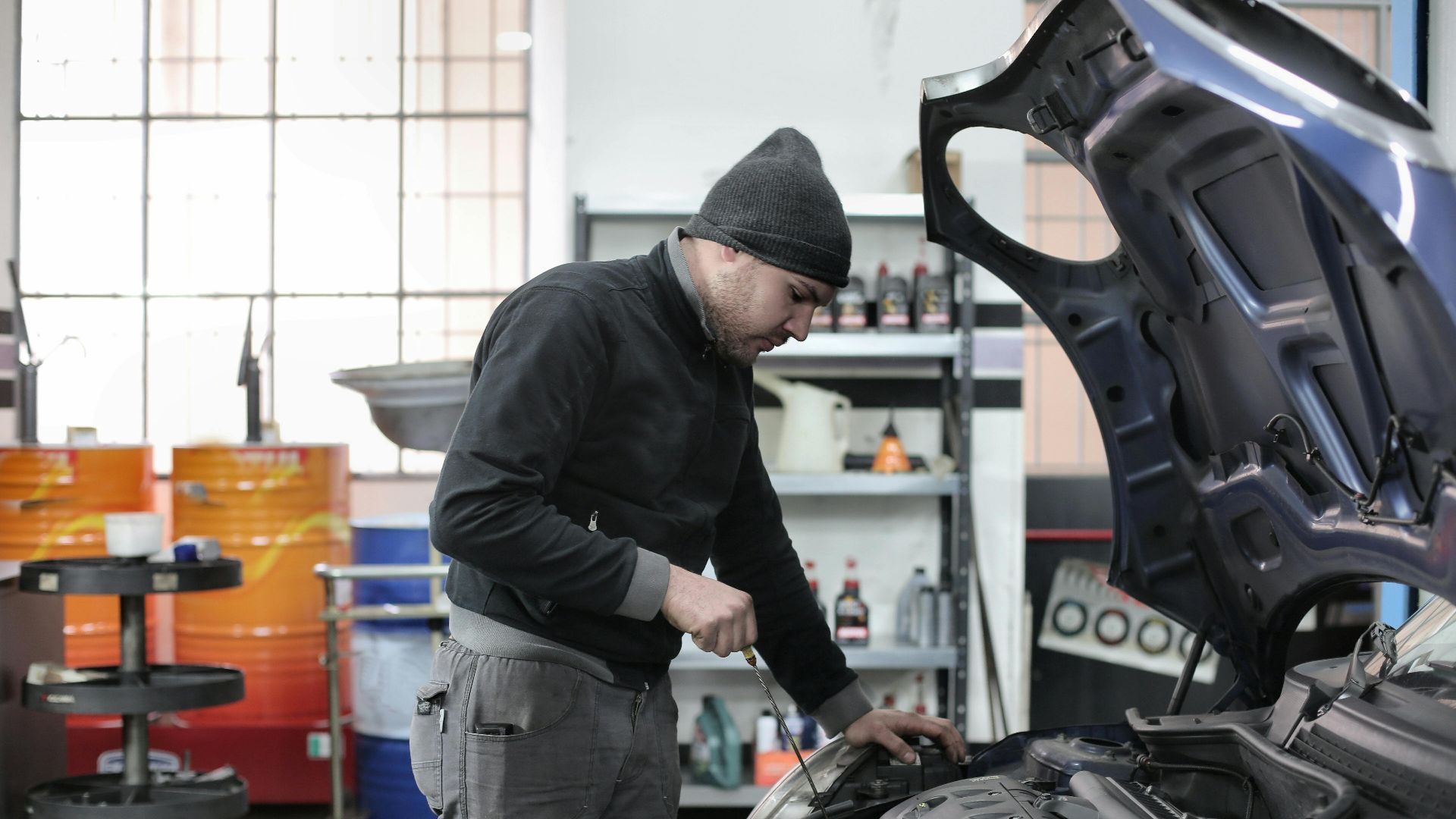Mechanic checking a car engine in a garage, ensuring quality maintenance and repair.