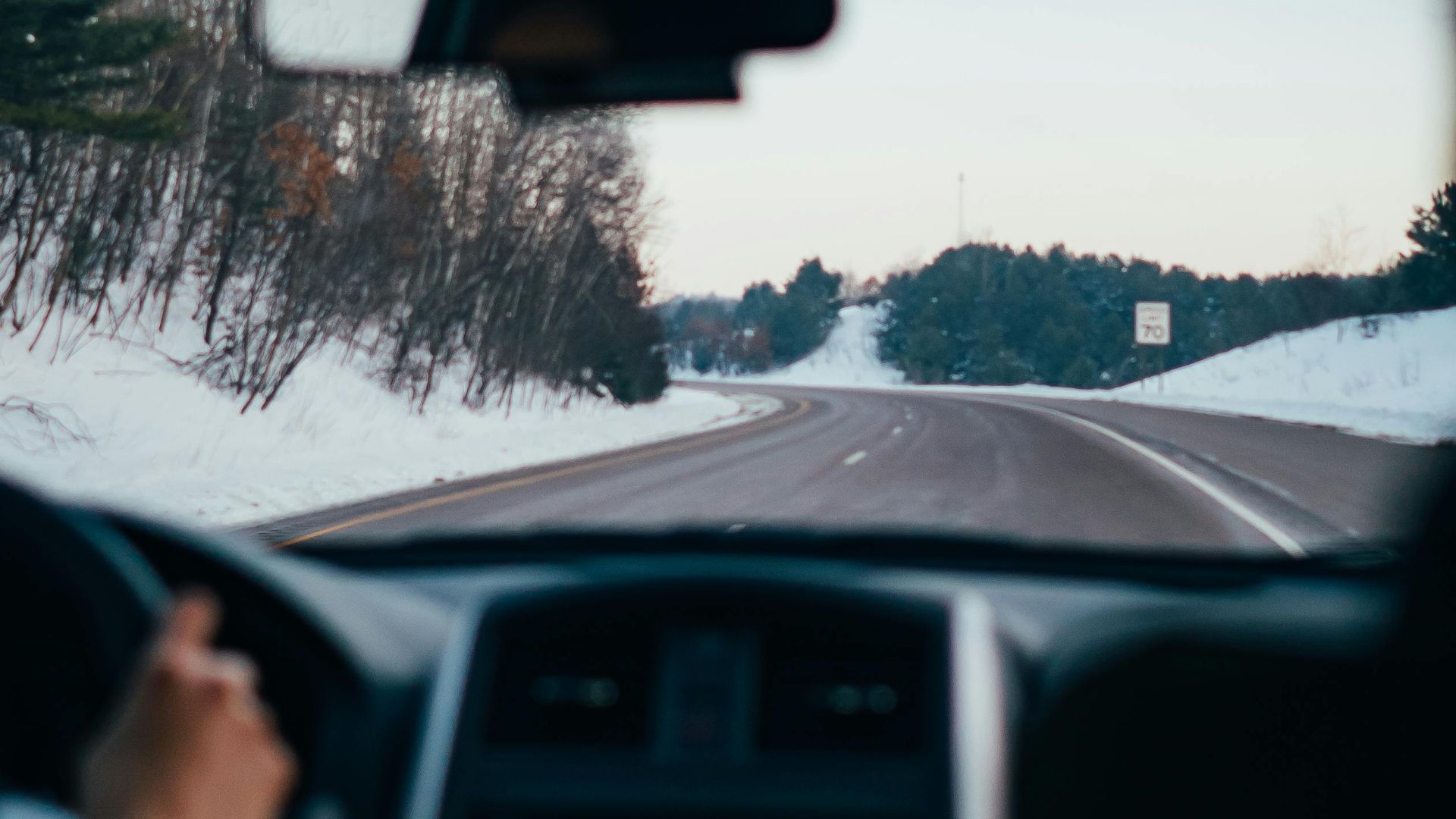 Driving along a snowy highway in winter, capturing the serene landscape and vehicle interior view.