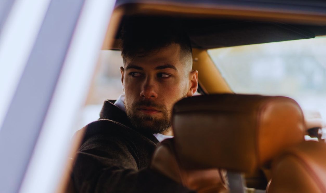 Guy sitting in car and looking in back window