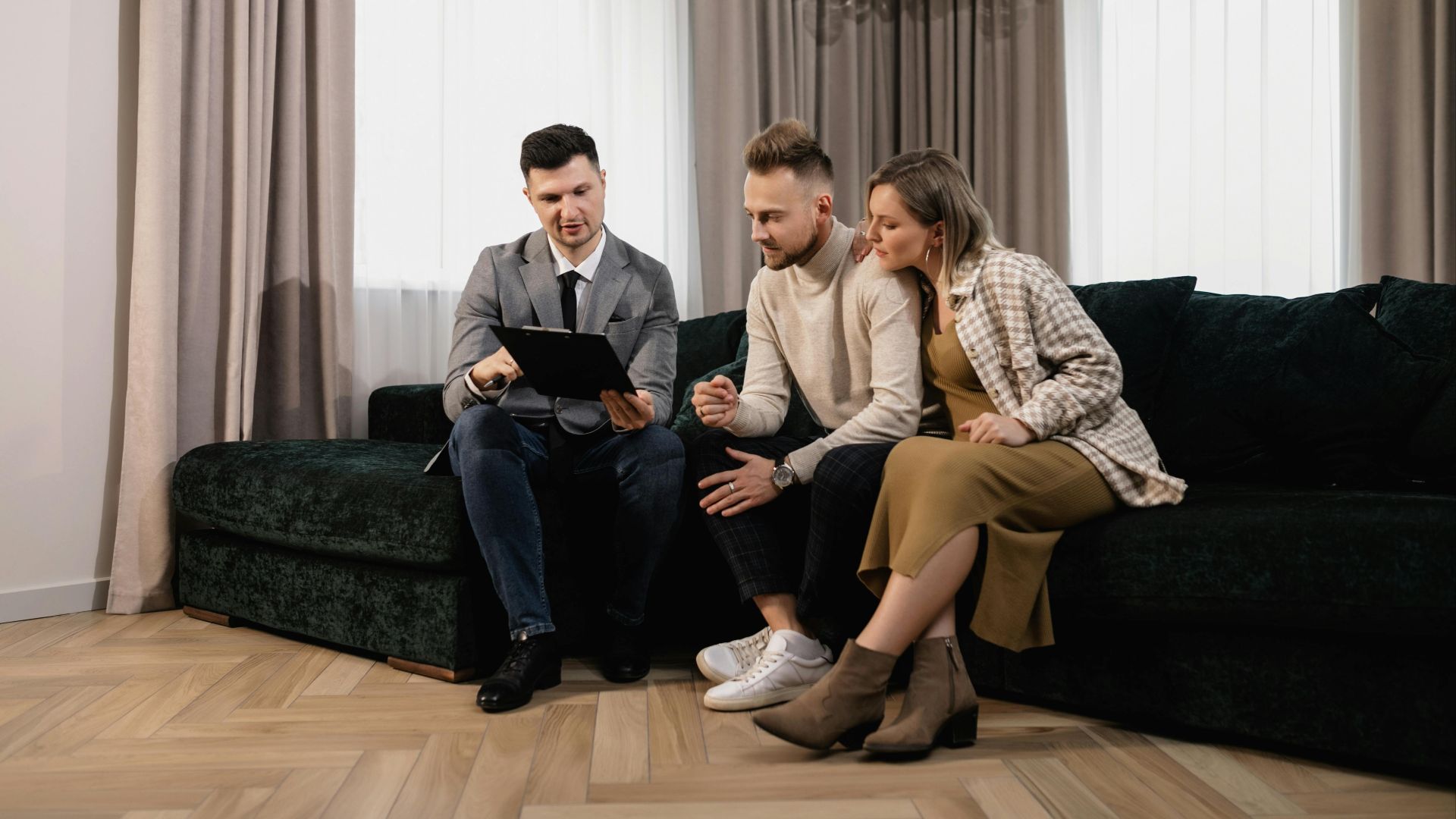 A real estate agent shows a property listing to a couple in a modern living room.