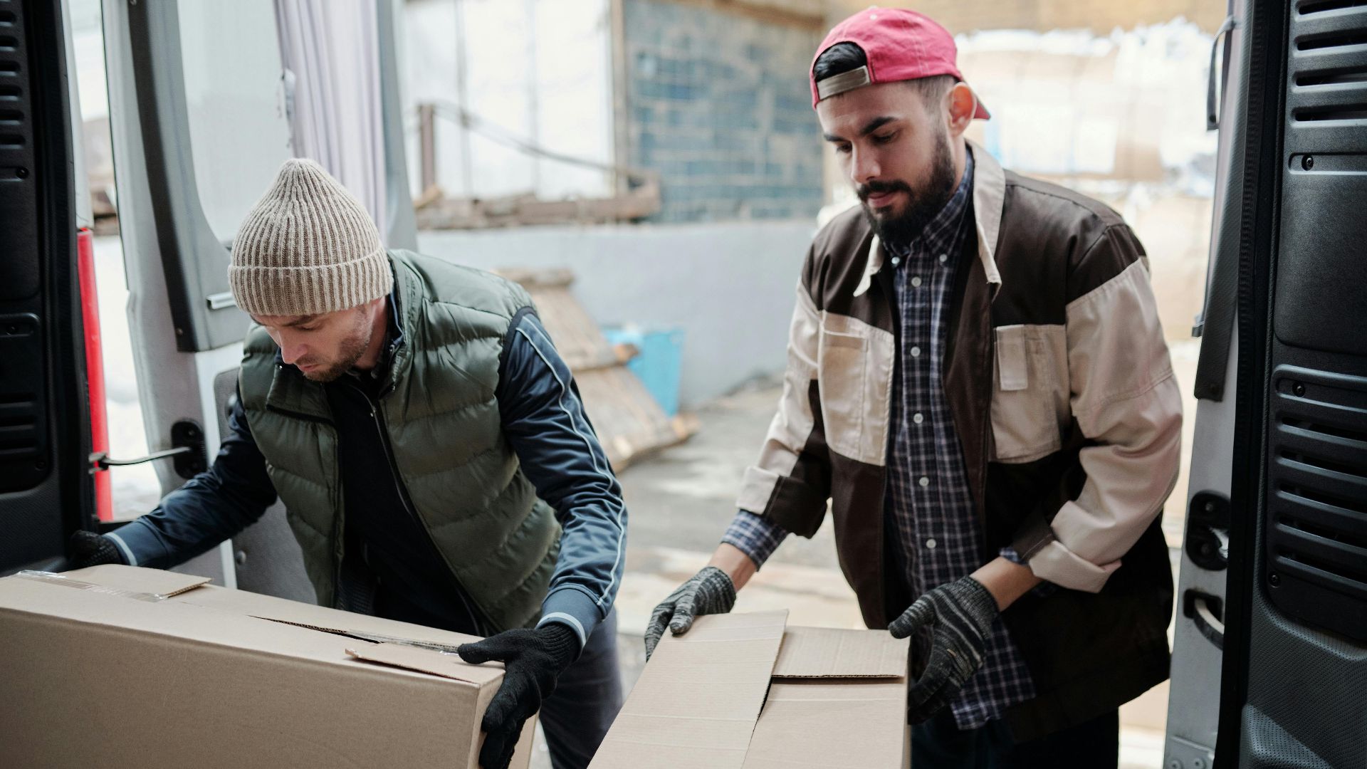 Two men handling boxes for delivery, working in a warehouse setting.