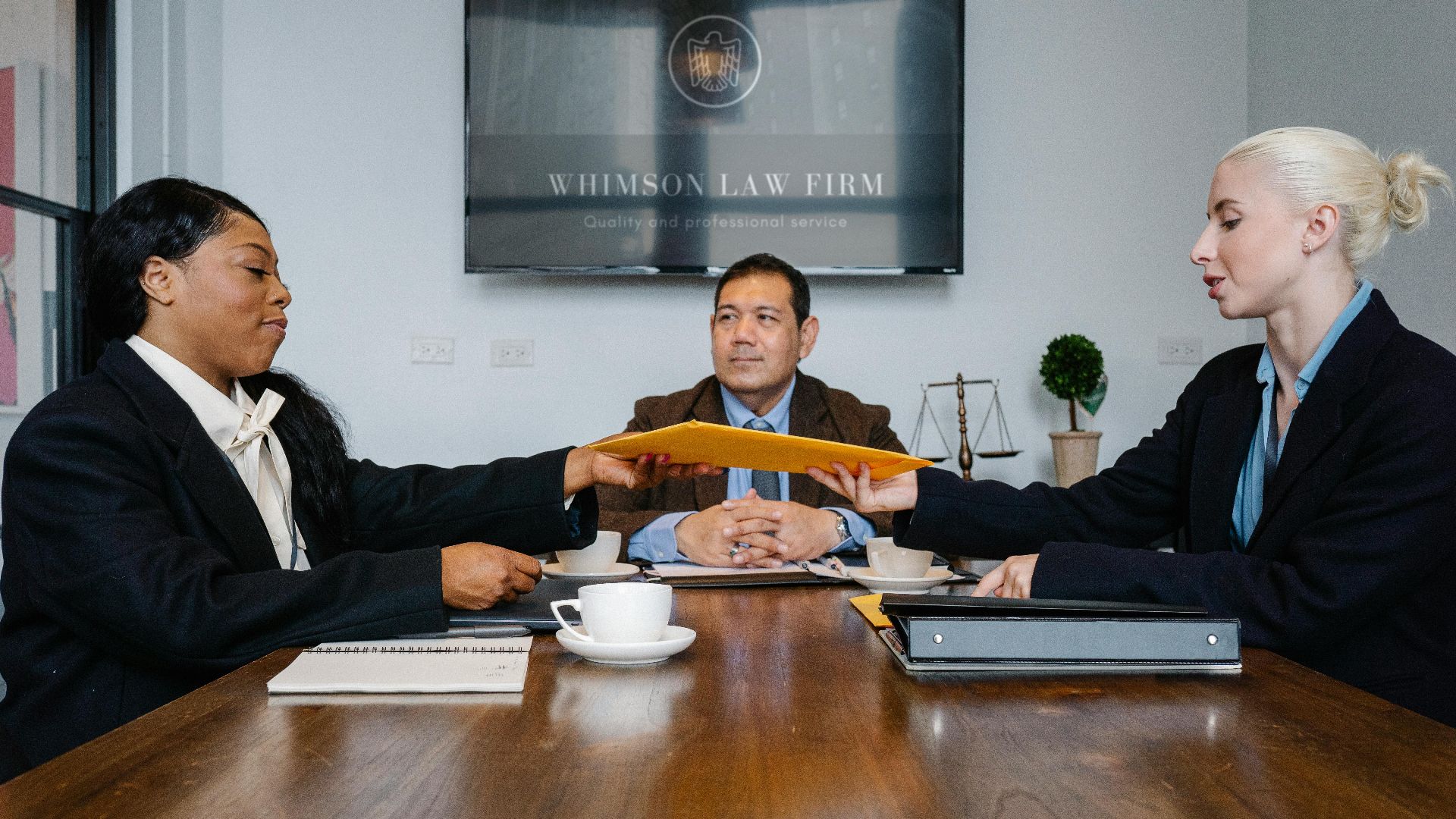 Group of cheerful diverse colleagues discussing court decision at table with notepad and cup