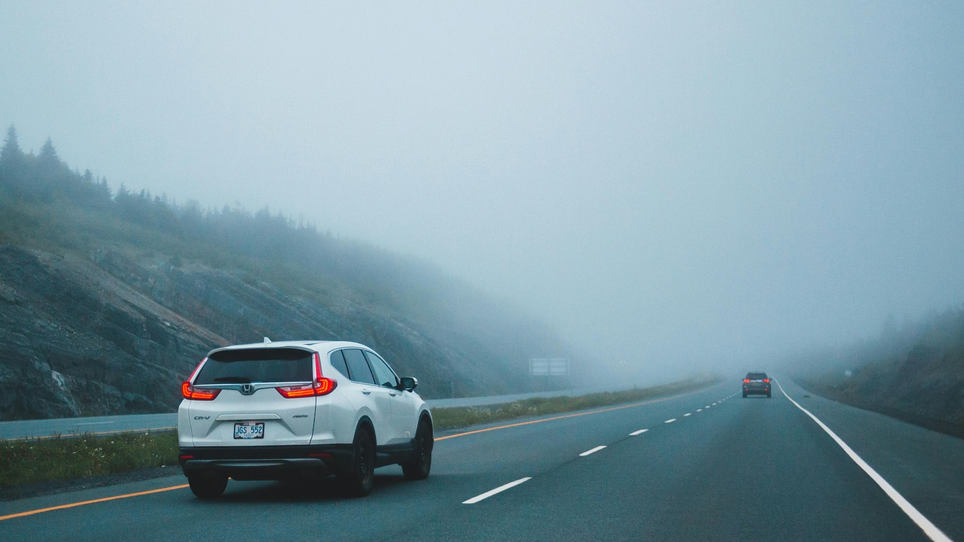 Cars driving on a foggy highway, creating a mysterious and serene atmosphere.