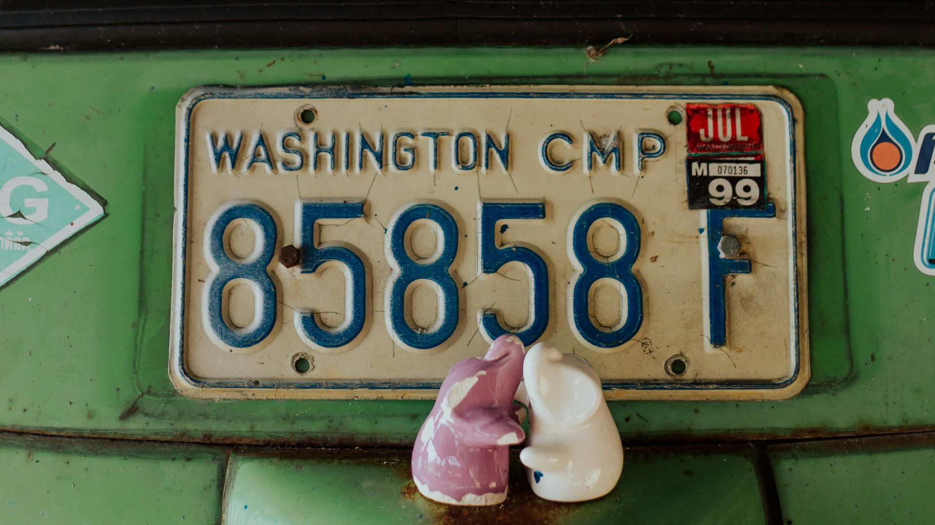 Close-up of a vintage car window showcasing a Washington license plate and figurines.
