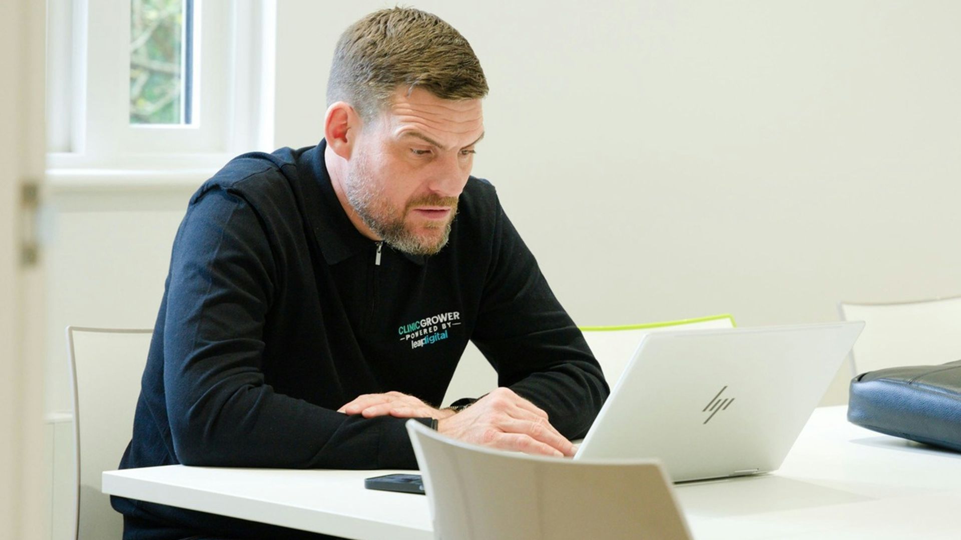 Man working on laptop at a white table.