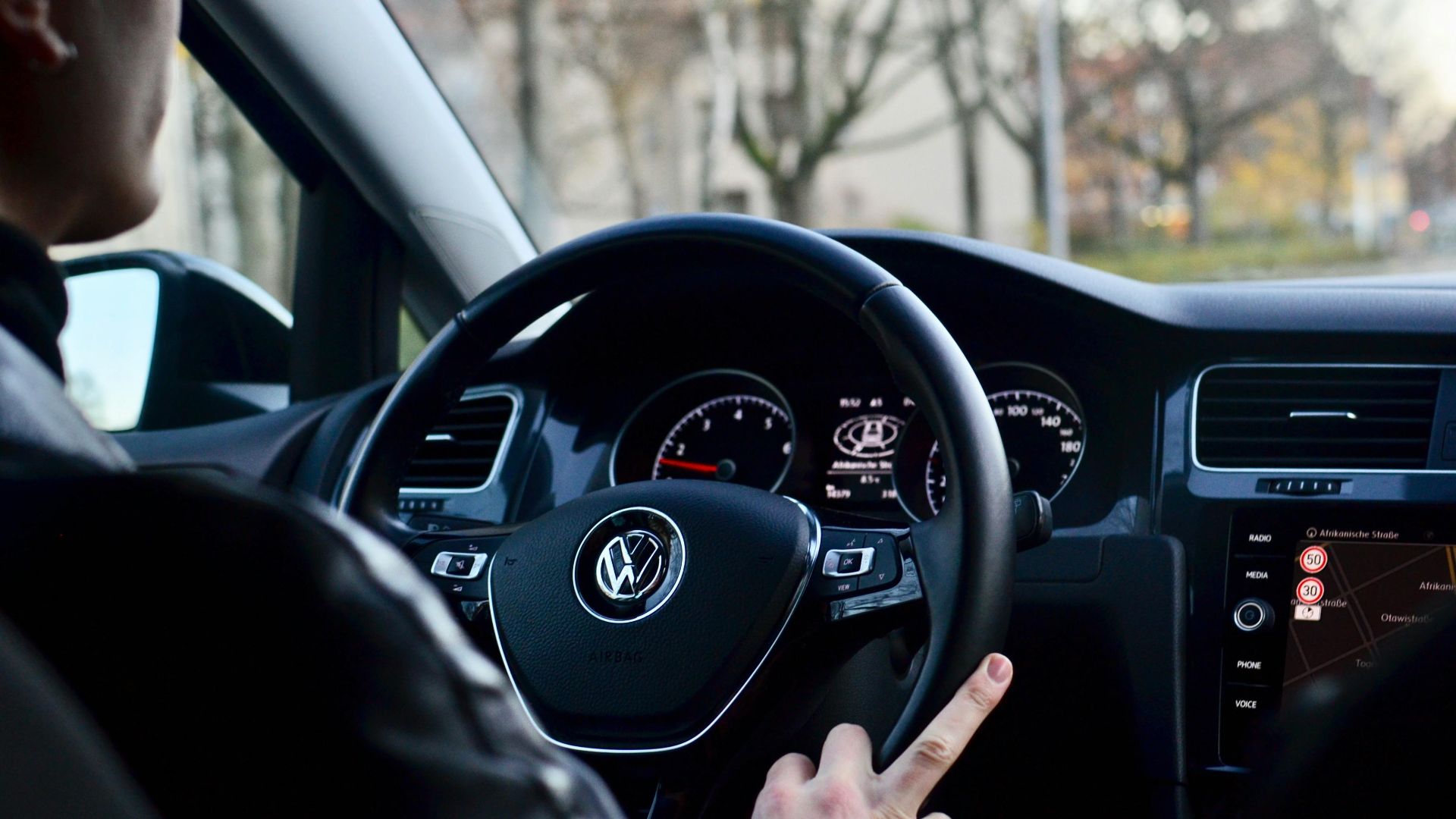 Back view of crop anonymous male driving contemporary transport while turning steering wheel in daylight
