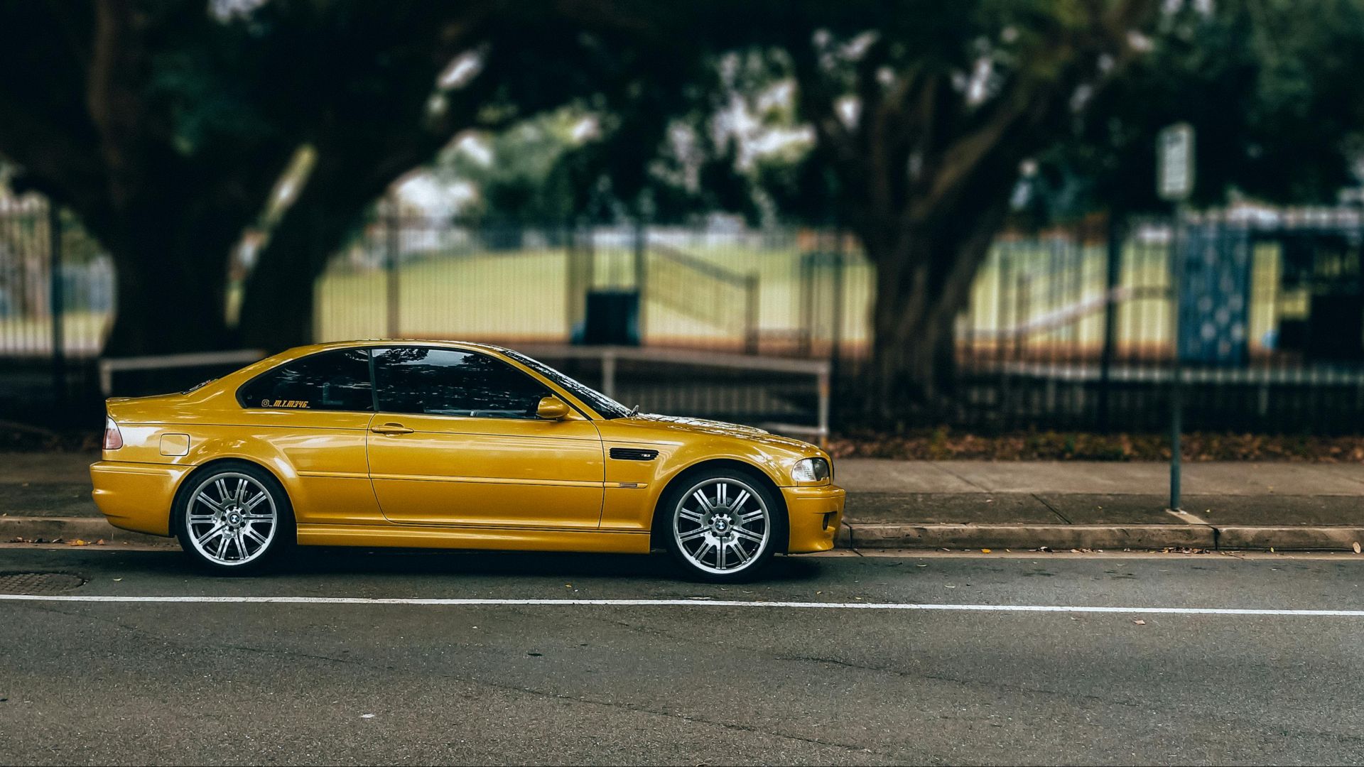 A stylish yellow car parked on an urban street with a blurred natural background.
