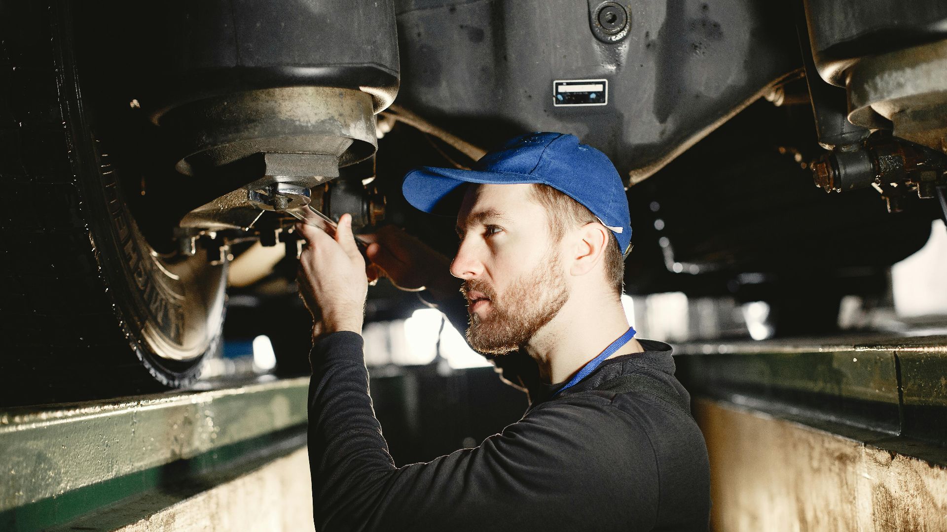 Auto mechanic working diligently on vehicle in workshop setting. Expertise in repair and maintenance.