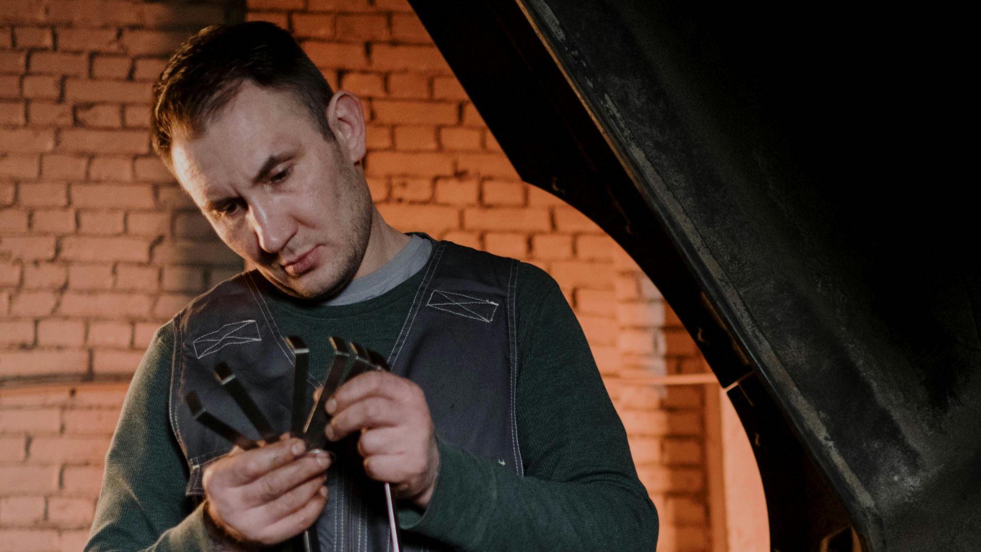 Mechanic in workshop tuning up engine parts with precision tools.