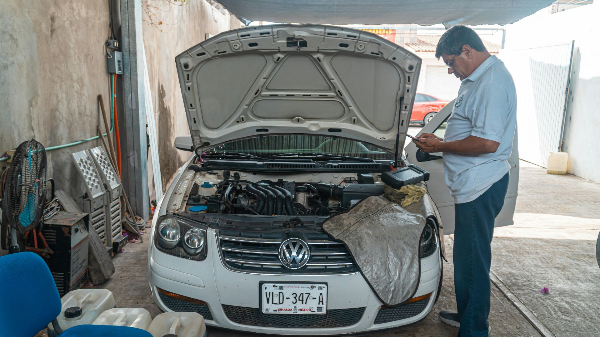 A mechanic examines a Volkswagen engine in a garage setting, focusing on car maintenance.