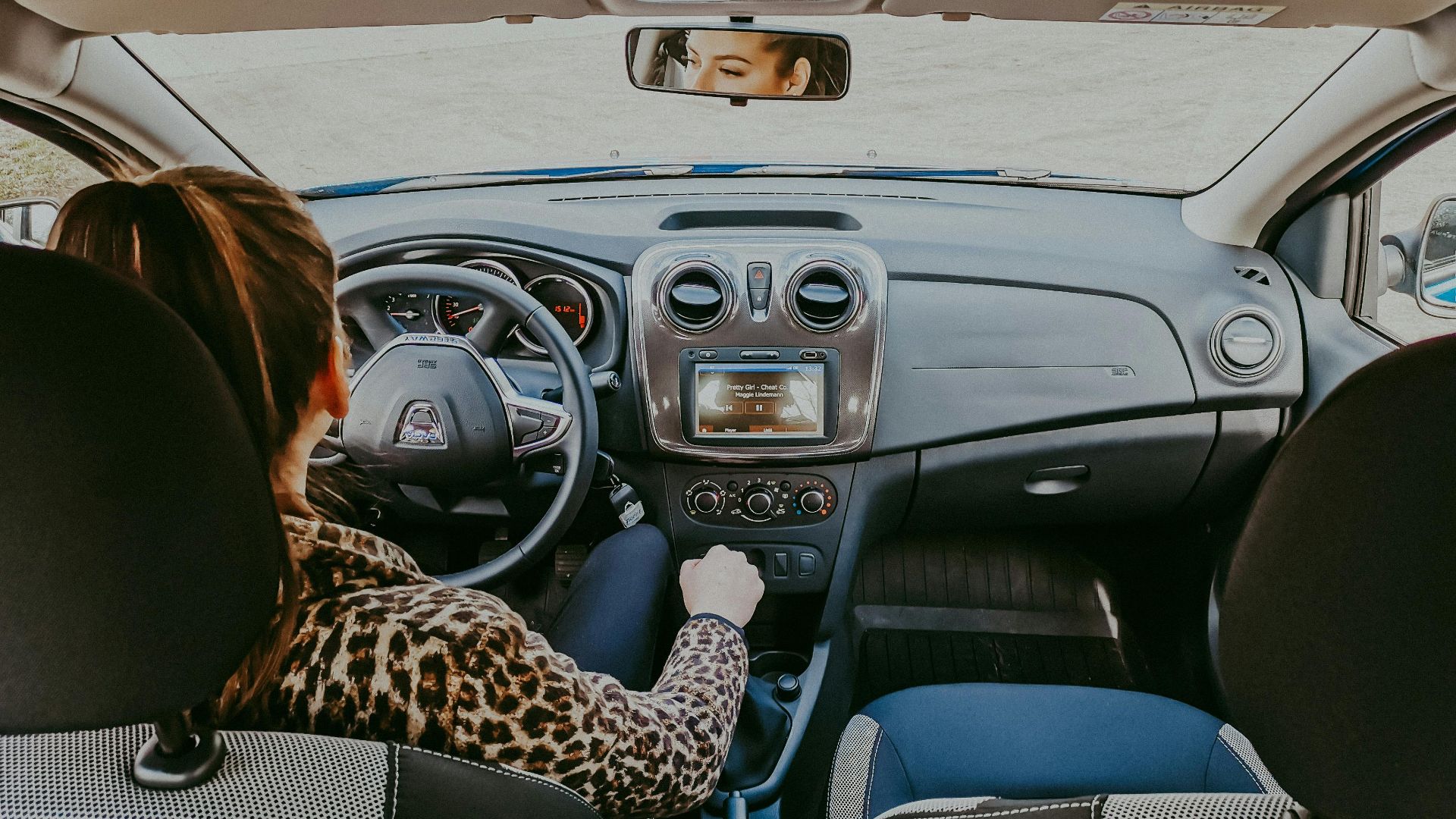 Back view of modern woman in stylish fur coat driving car confidently looking away