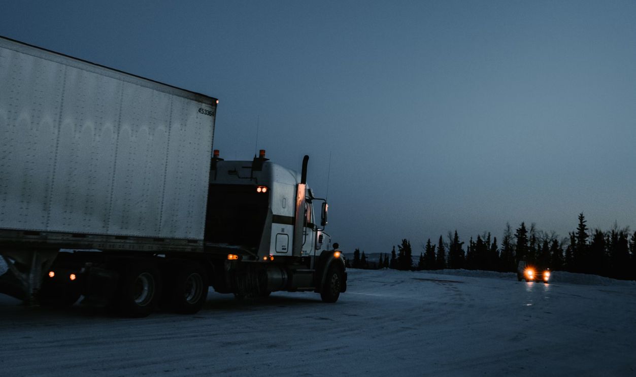 white and black freight truck traveling on road
