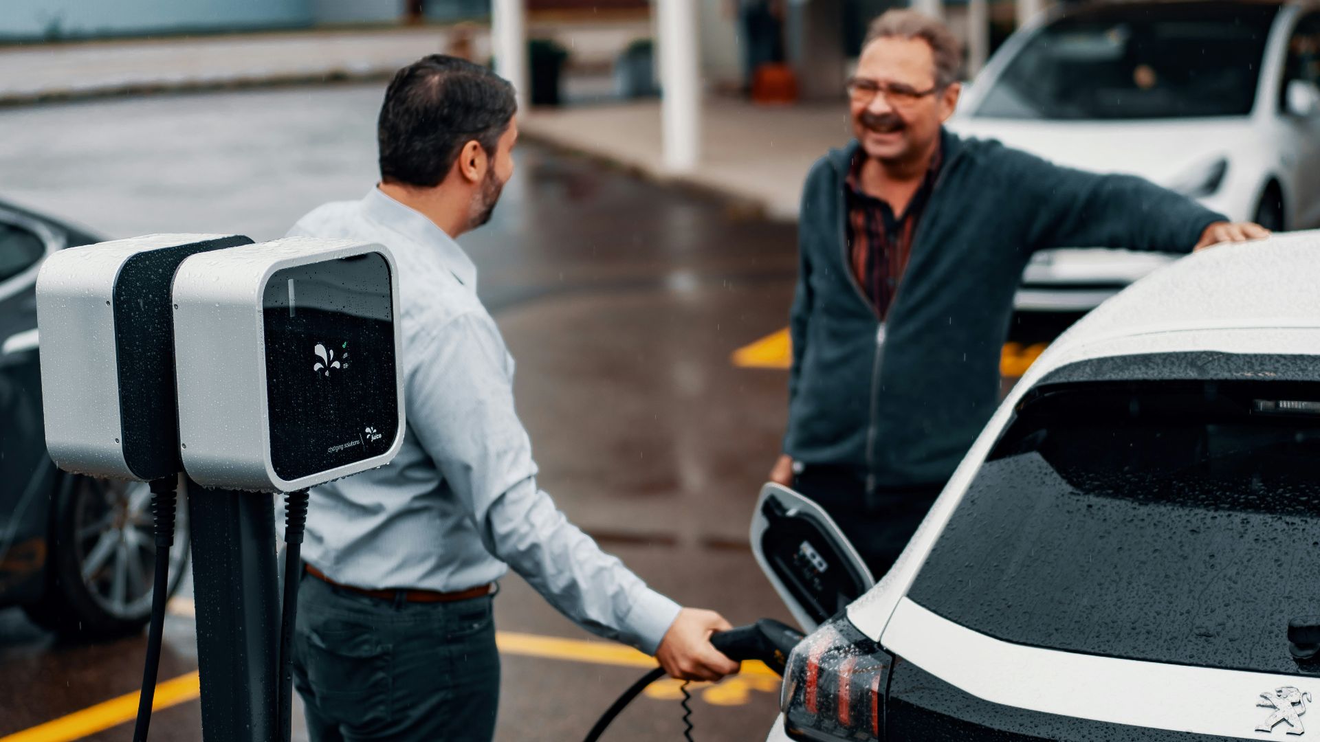 a couple of men standing next to a white car