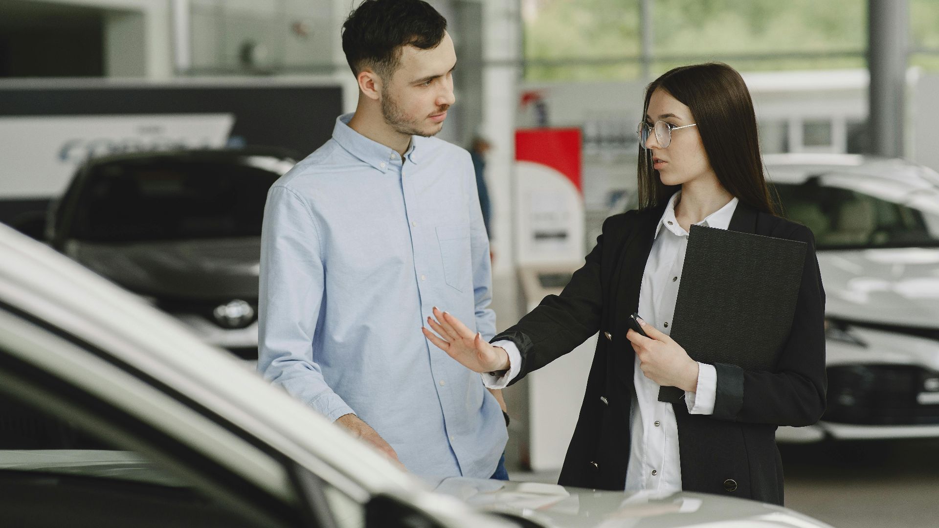 A salesperson and customer discussing car features in a dealership setting.