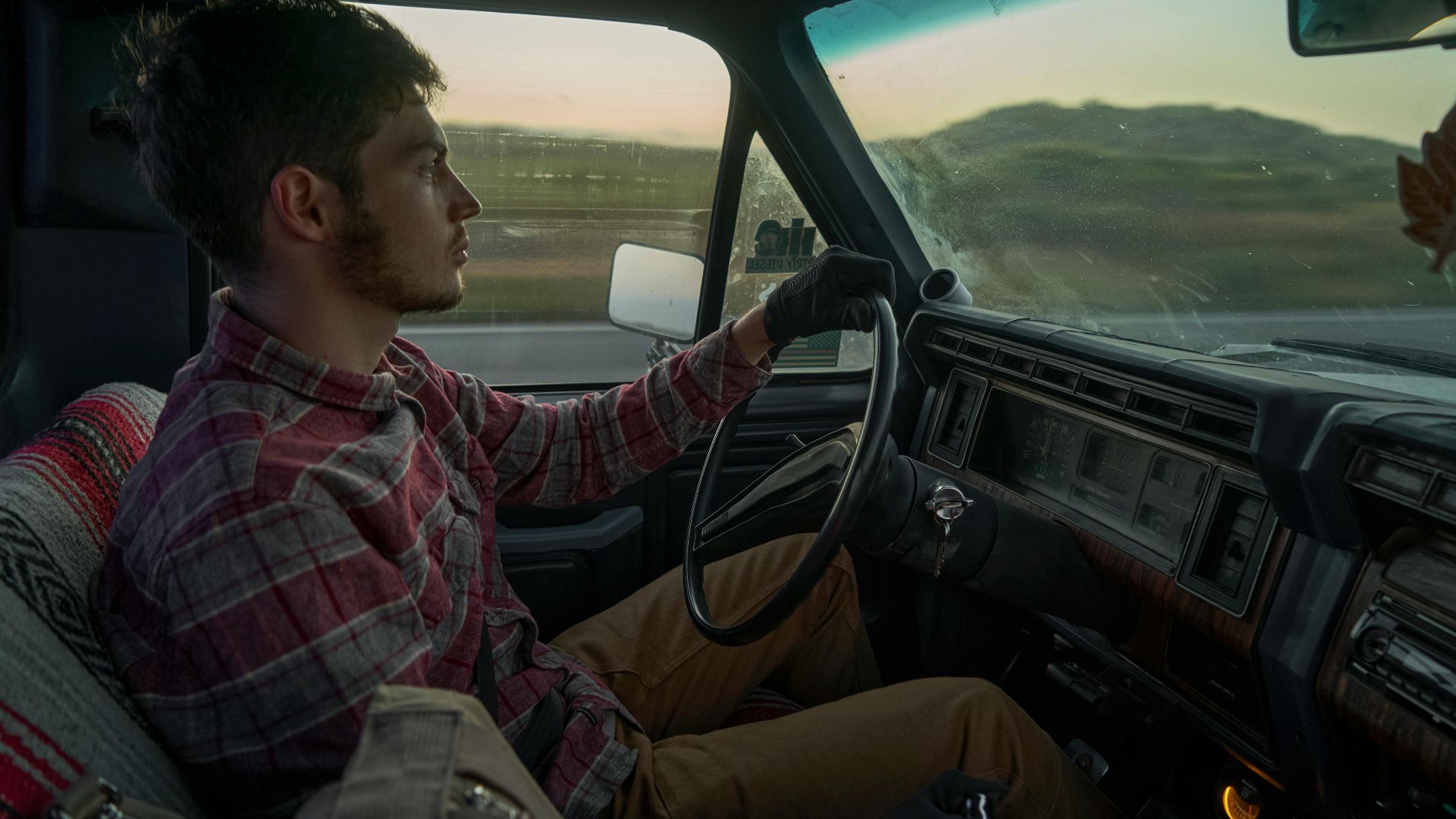 A young man drives a vintage car, showcasing scenic views and interior details.