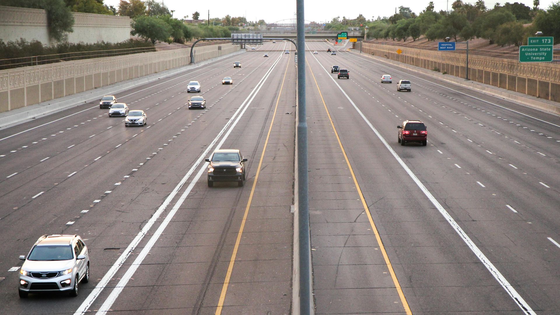 Aerial view of a deserted highway with few cars during dusk, depicting calm traffic conditions.