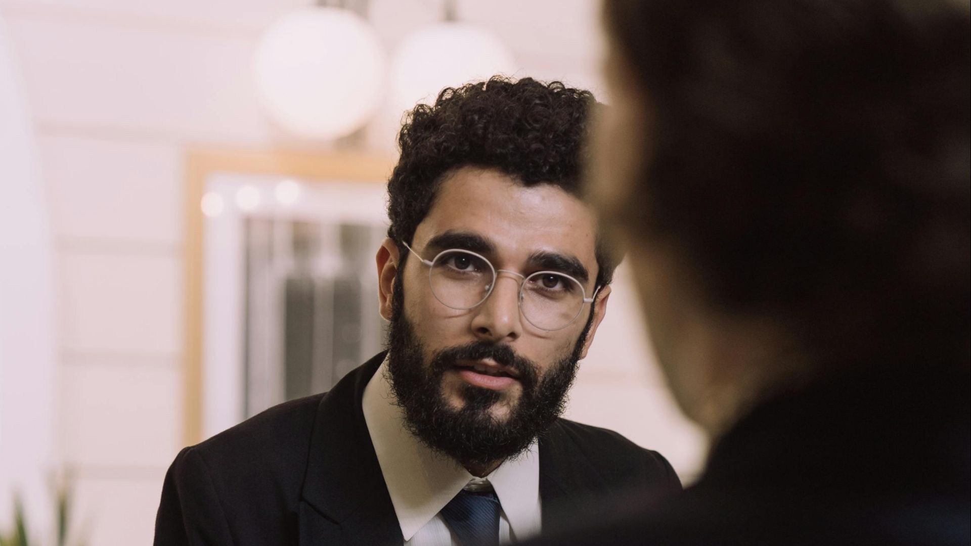 A professional businessman checks in at a hotel reception, engaging with a concierge.