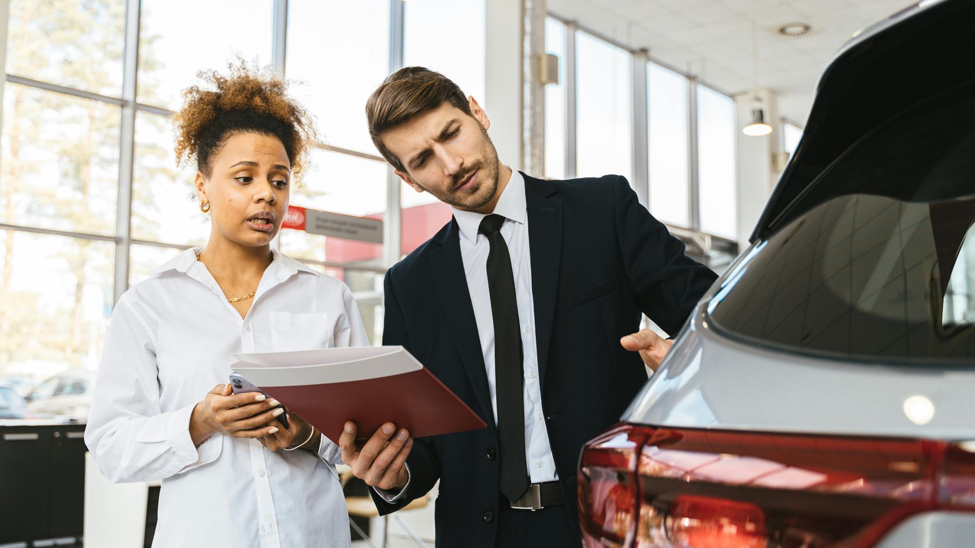 A professional consultation at a car dealership involving a sales agent and a customer discussing a vehicle purchase.