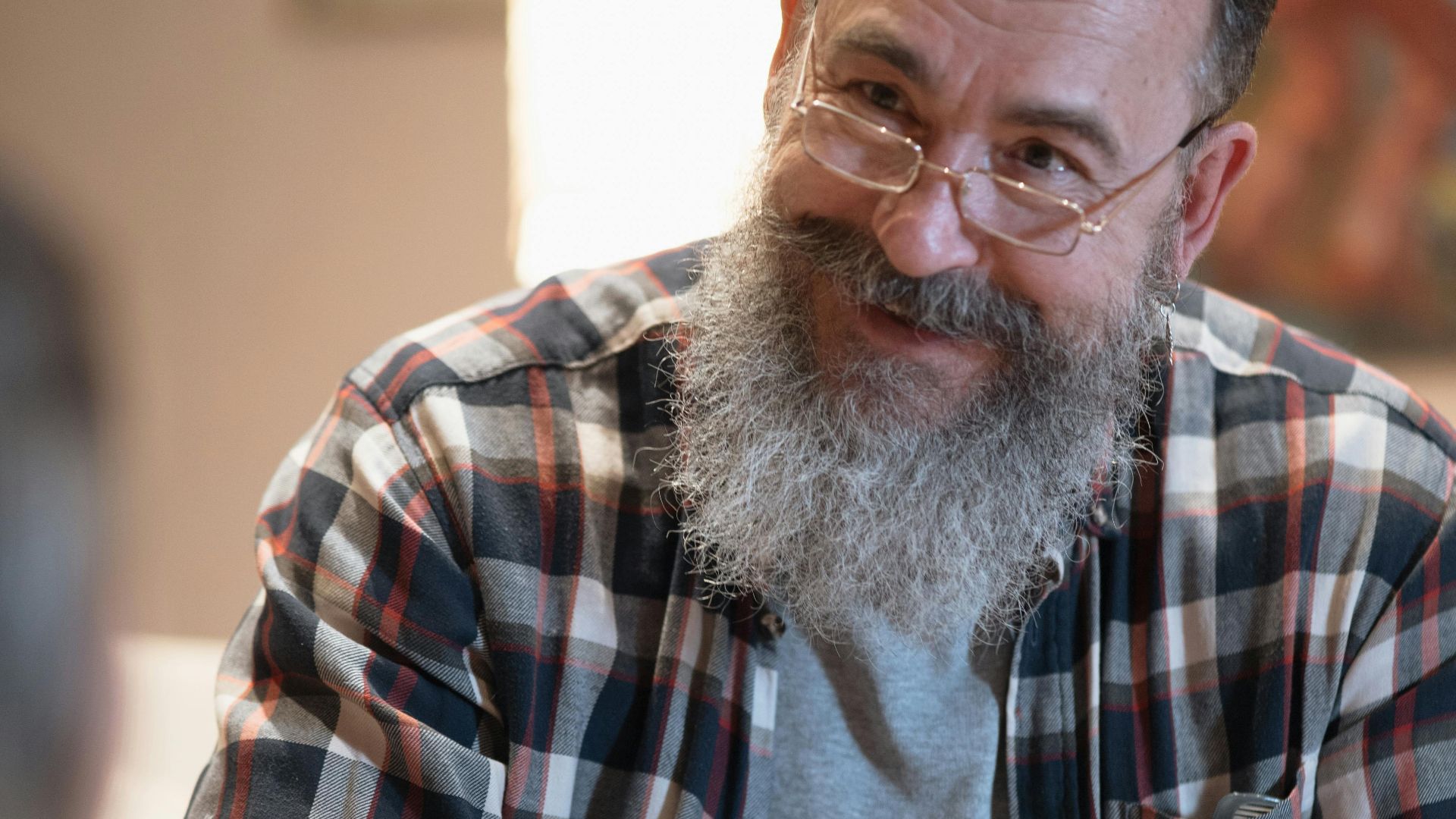 Senior man with a beard and glasses enjoys playing board games indoors. Cozy home environment.