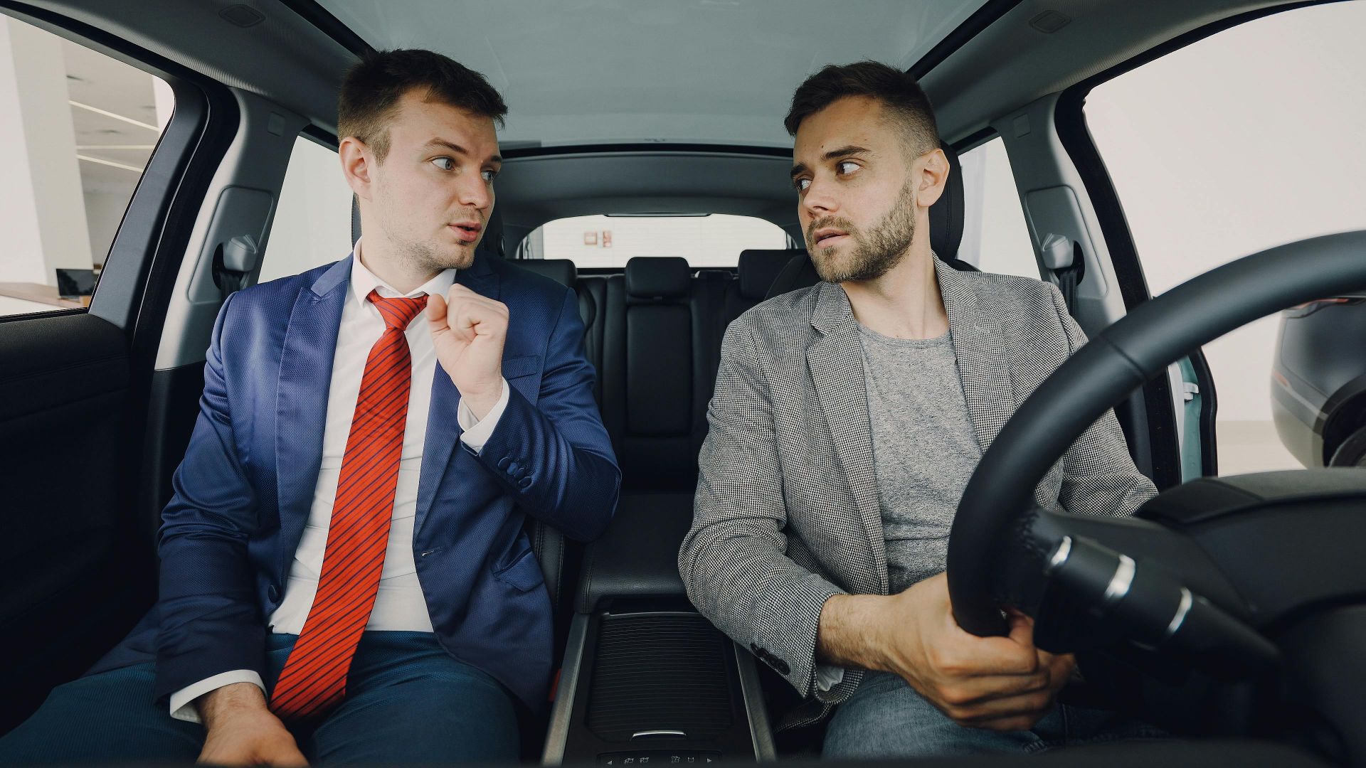 Two businessmen in a car engage in conversation, focusing on discussion details.