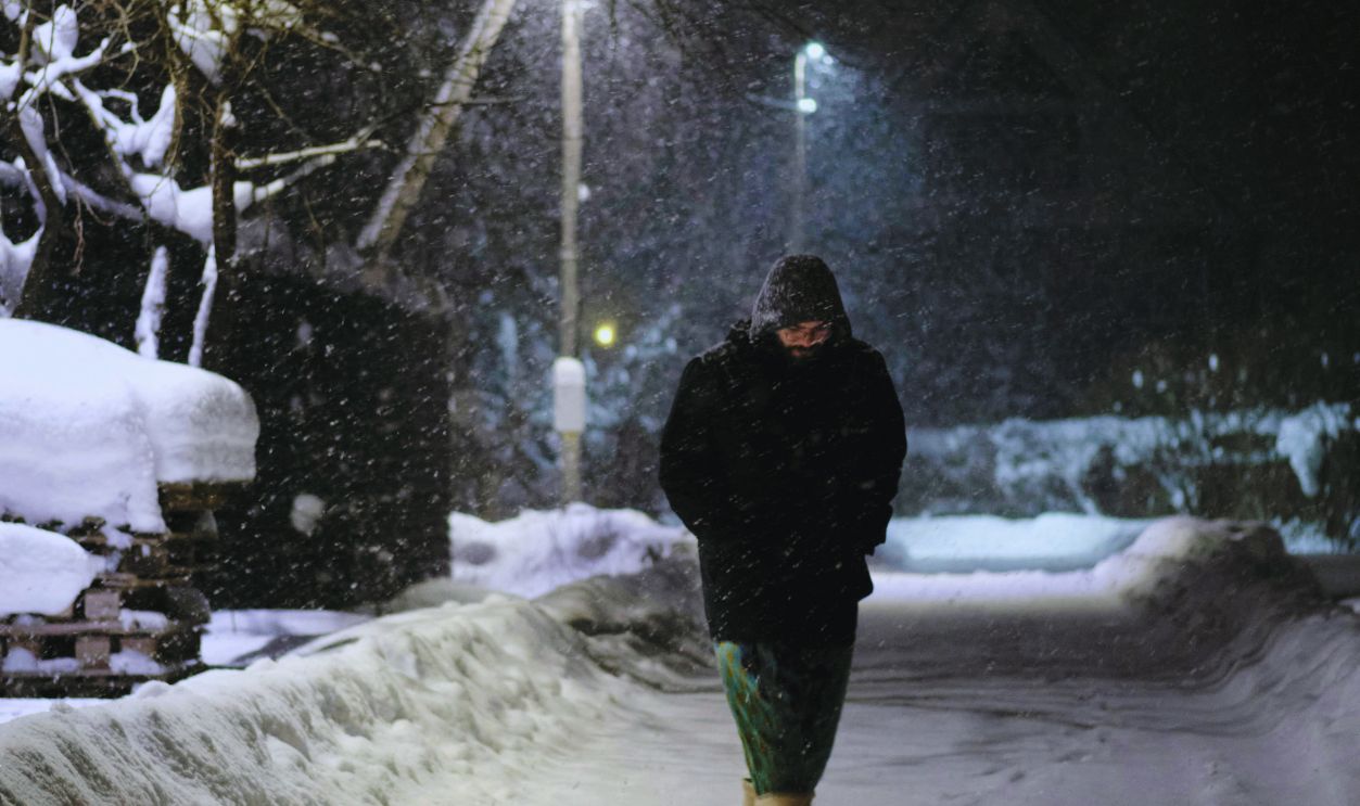 A Person Walking on a Snow-Covered Field at Night