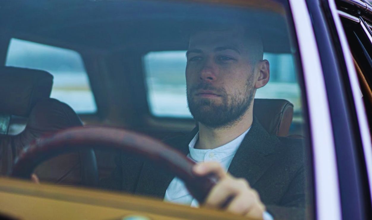 A Bearded Man Driving a Car