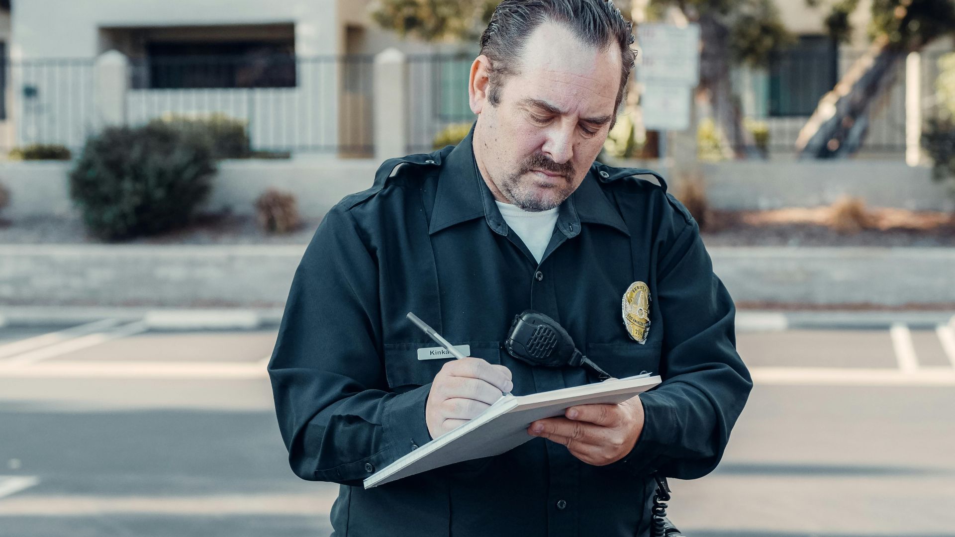 Police officer in uniform writing a ticket on a clipboard outdoors.