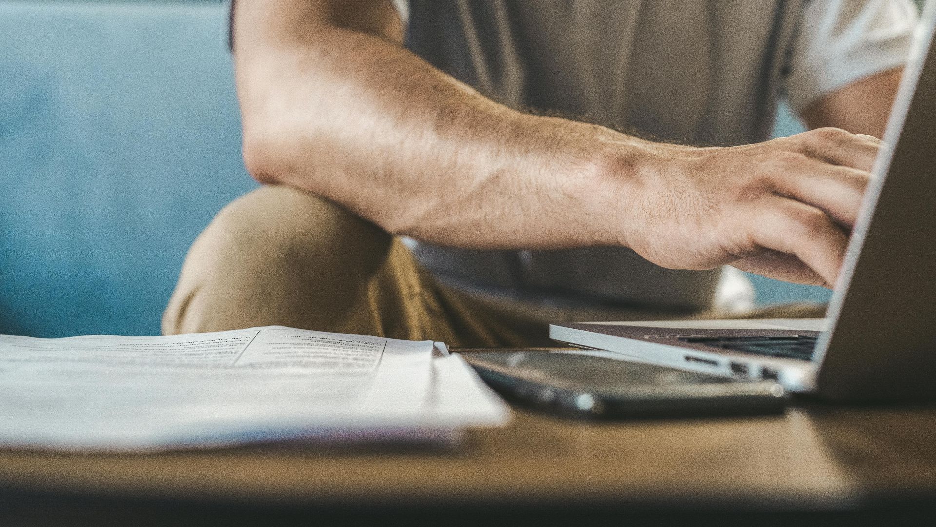 A man typing on a laptop at home, using wireless technology.