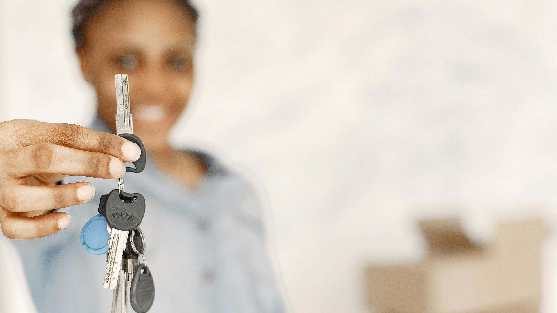 Close-up of a woman holding keys with a blurred background, symbolizing a new home or real estate concept.